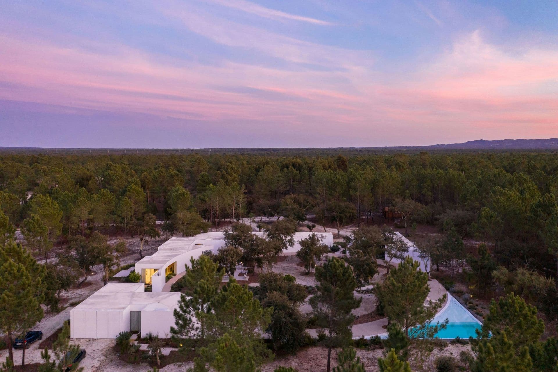 Aerial view of the white villa compound and pool among the pines at dusk at The Spirit of Joy, Comporta