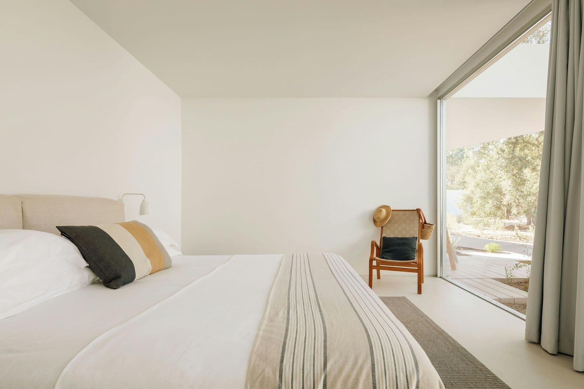 White bedroom opening through glass to the cork oaks at The Spirit of Joy, Comporta