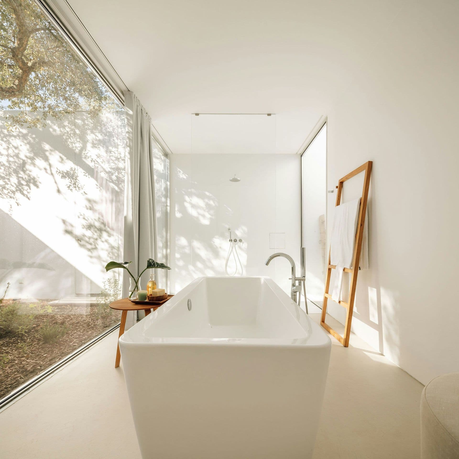 Bathroom with a freestanding bath beside a glazed garden courtyard at The Spirit of Joy, Comporta