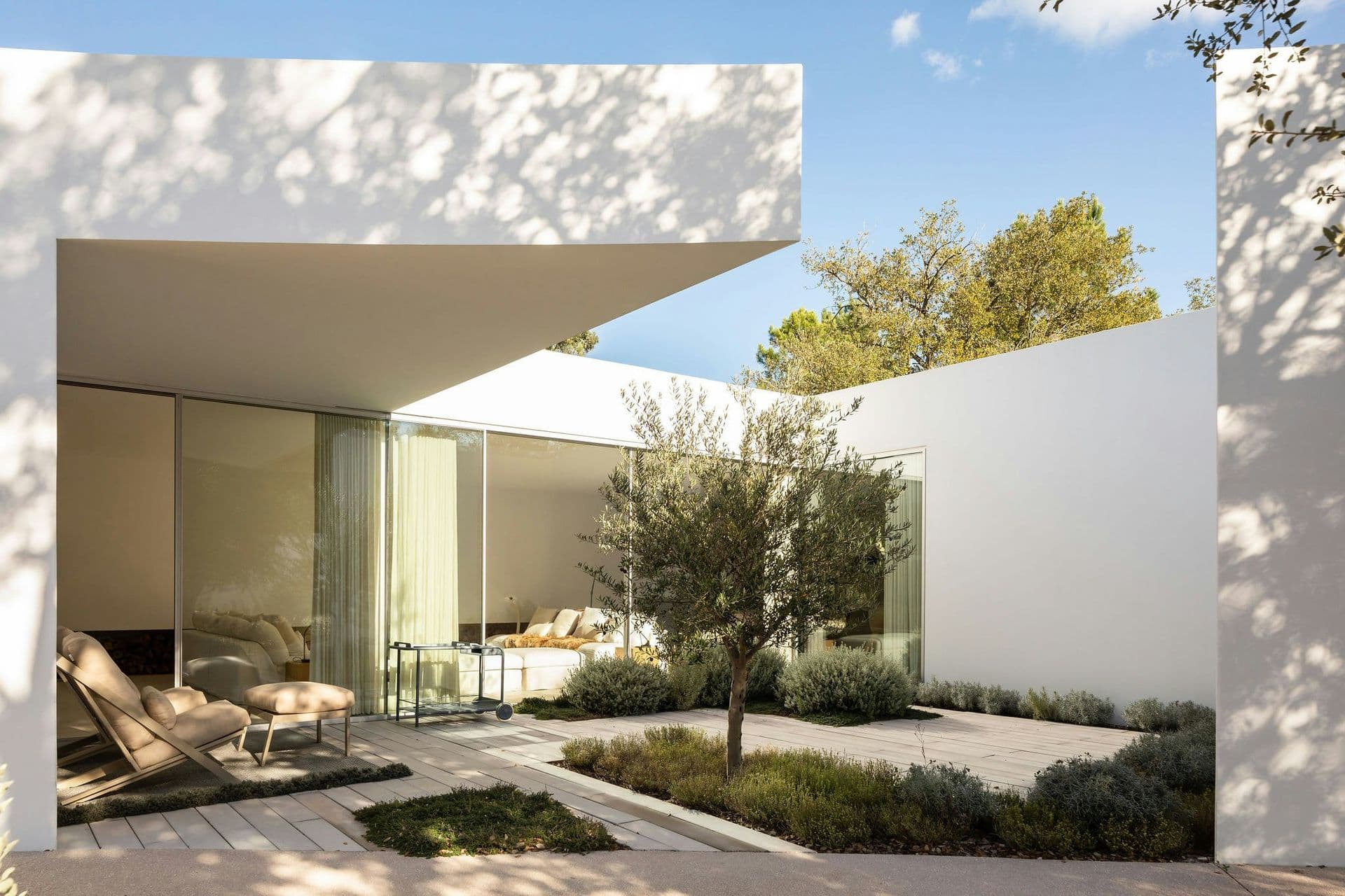 White courtyard with an olive tree and outdoor seating at The Spirit of Joy, Comporta