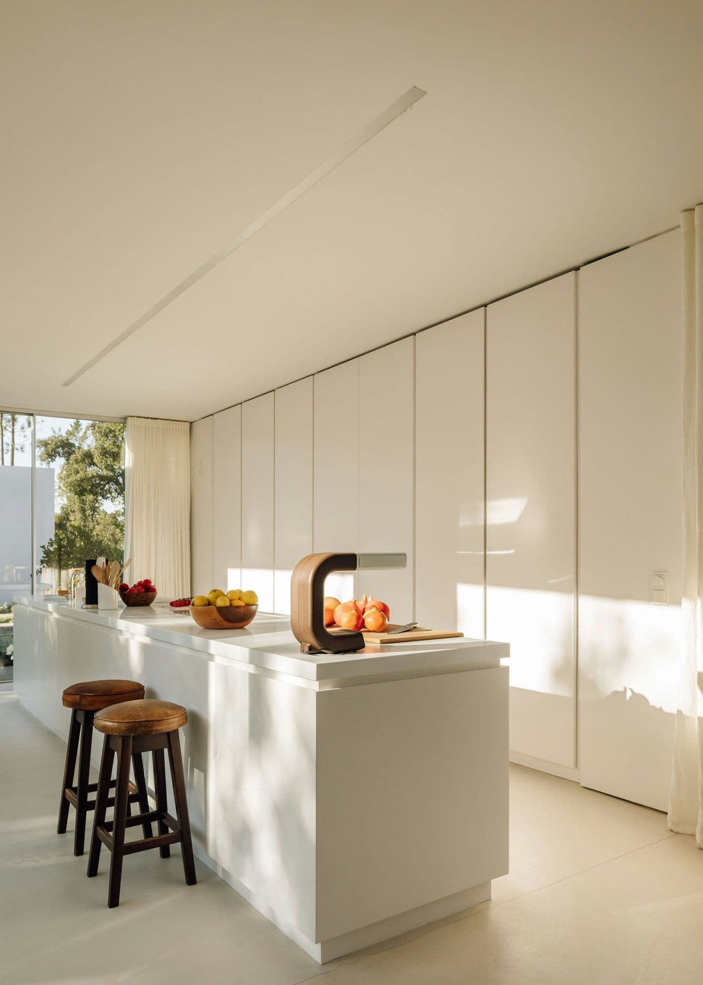 White minimalist kitchen with an island and bar stools at The Spirit of Joy, Comporta