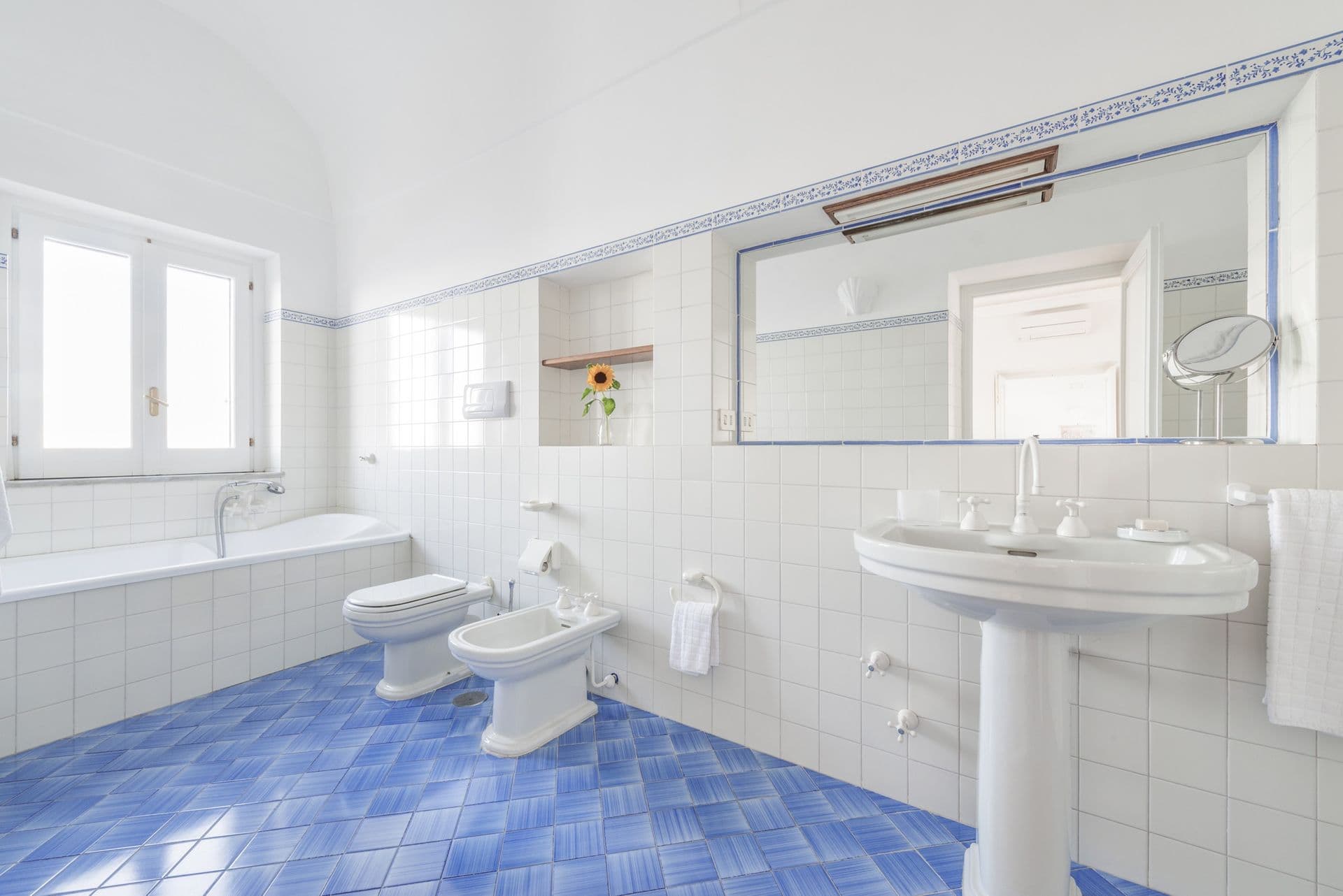 Bathroom with a bathtub and blue majolica-tiled floor at Arch Above the Sea, Amalfi Coast
