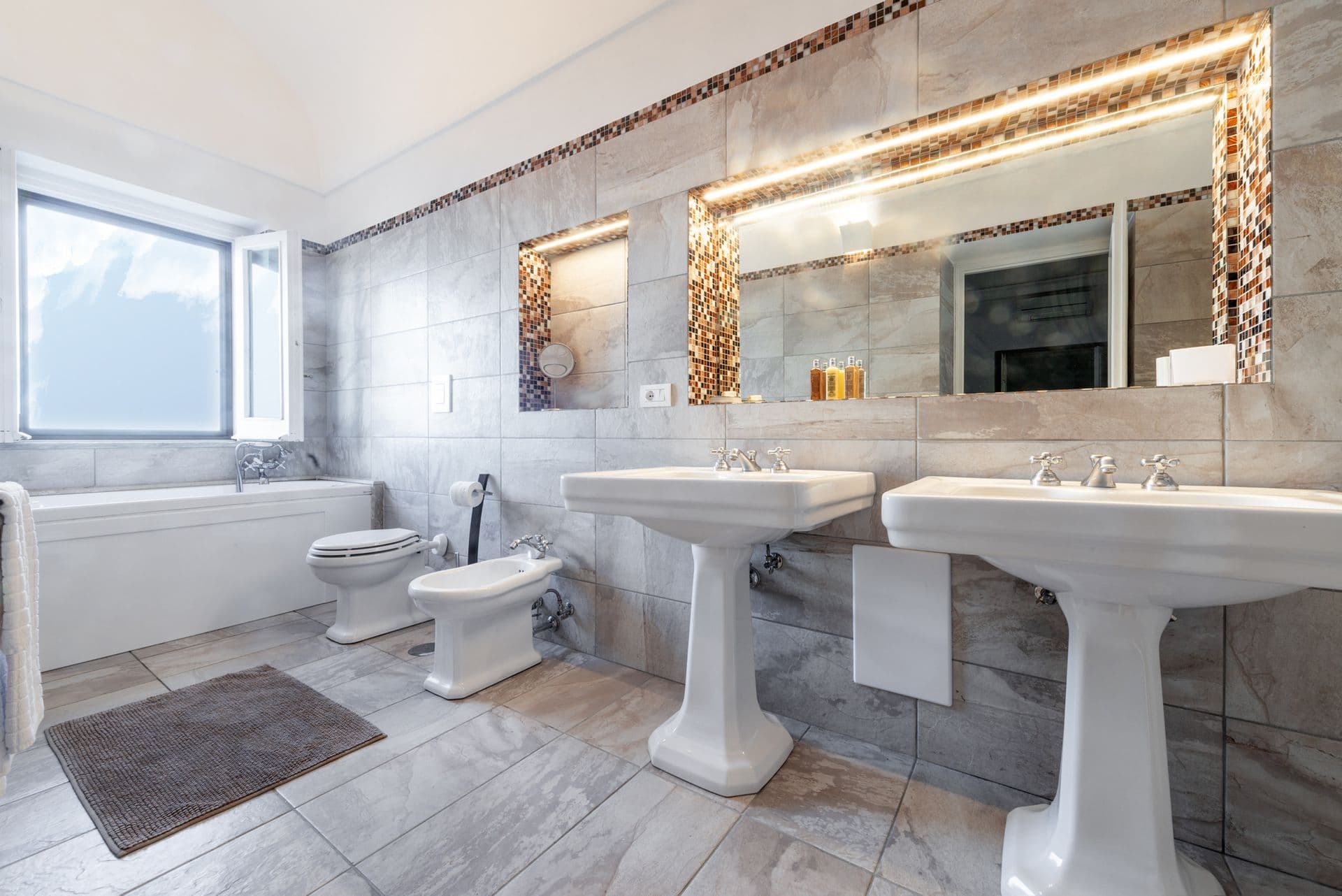 Marble bathroom with twin pedestal basins and a bathtub at Arch Above the Sea, Amalfi Coast