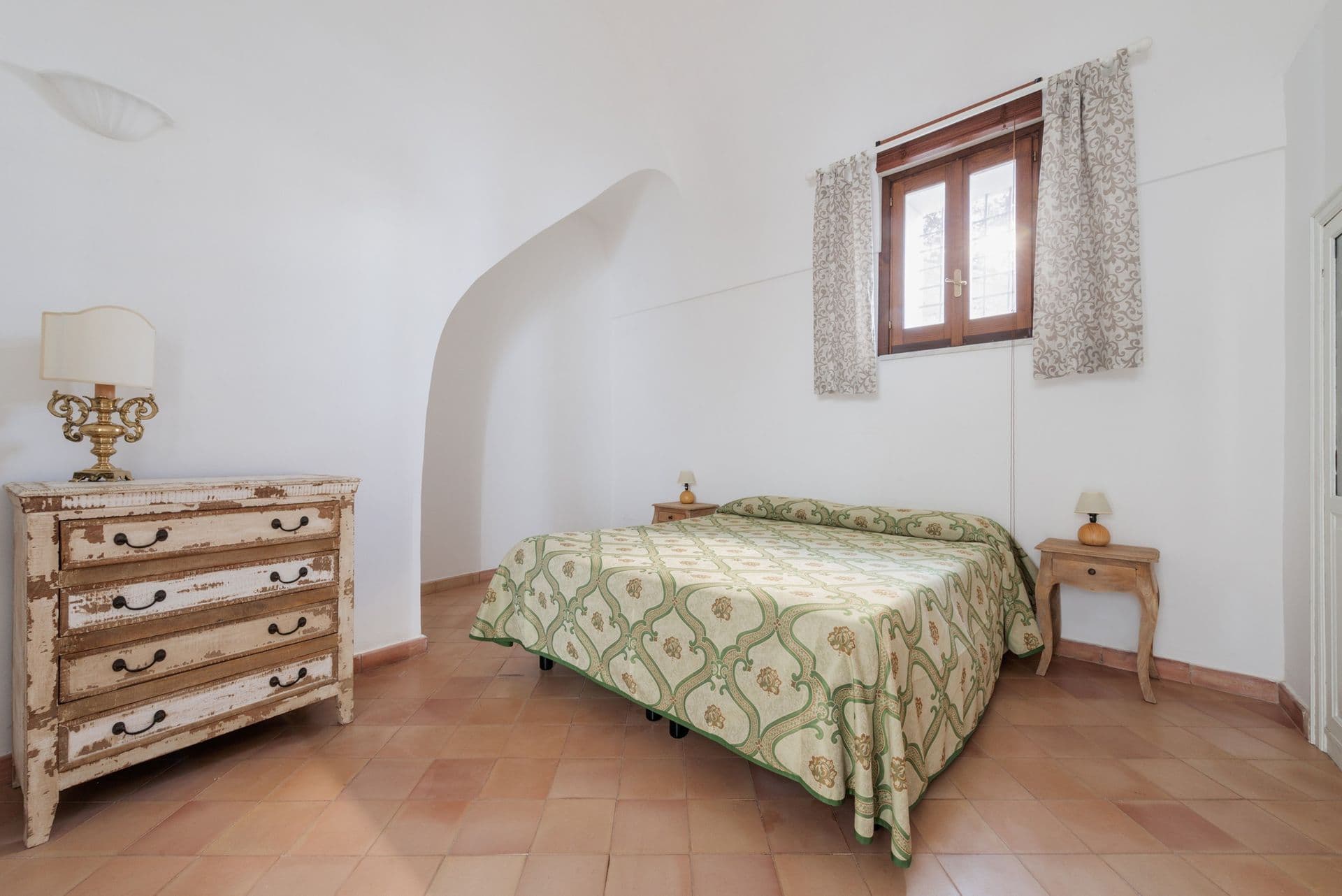 Double bedroom with a rustic dresser and terracotta floor at Arch Above the Sea, Amalfi Coast