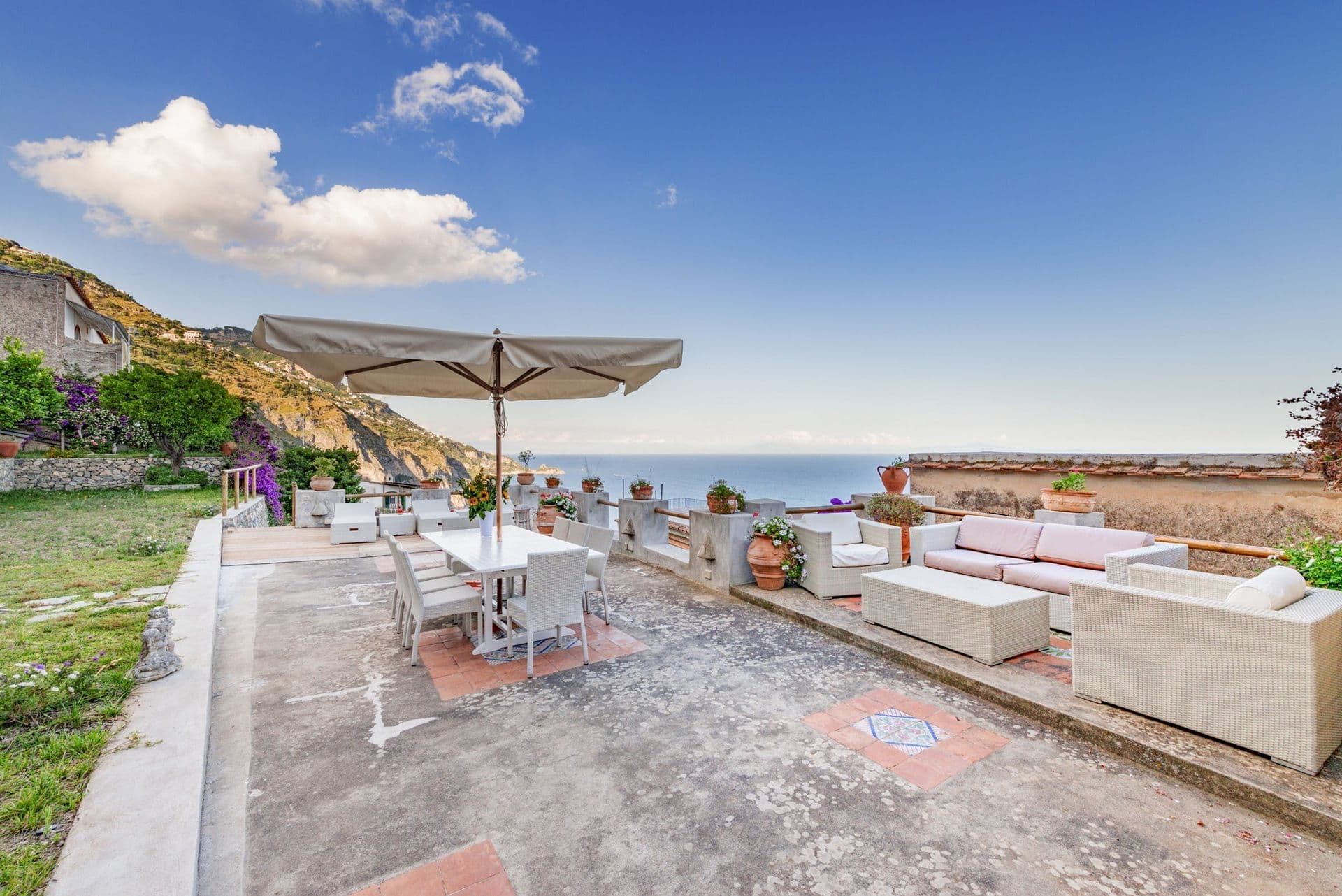 Outdoor dining table and sofas on a terrace overlooking the coast at Arch Above the Sea, Amalfi Coast