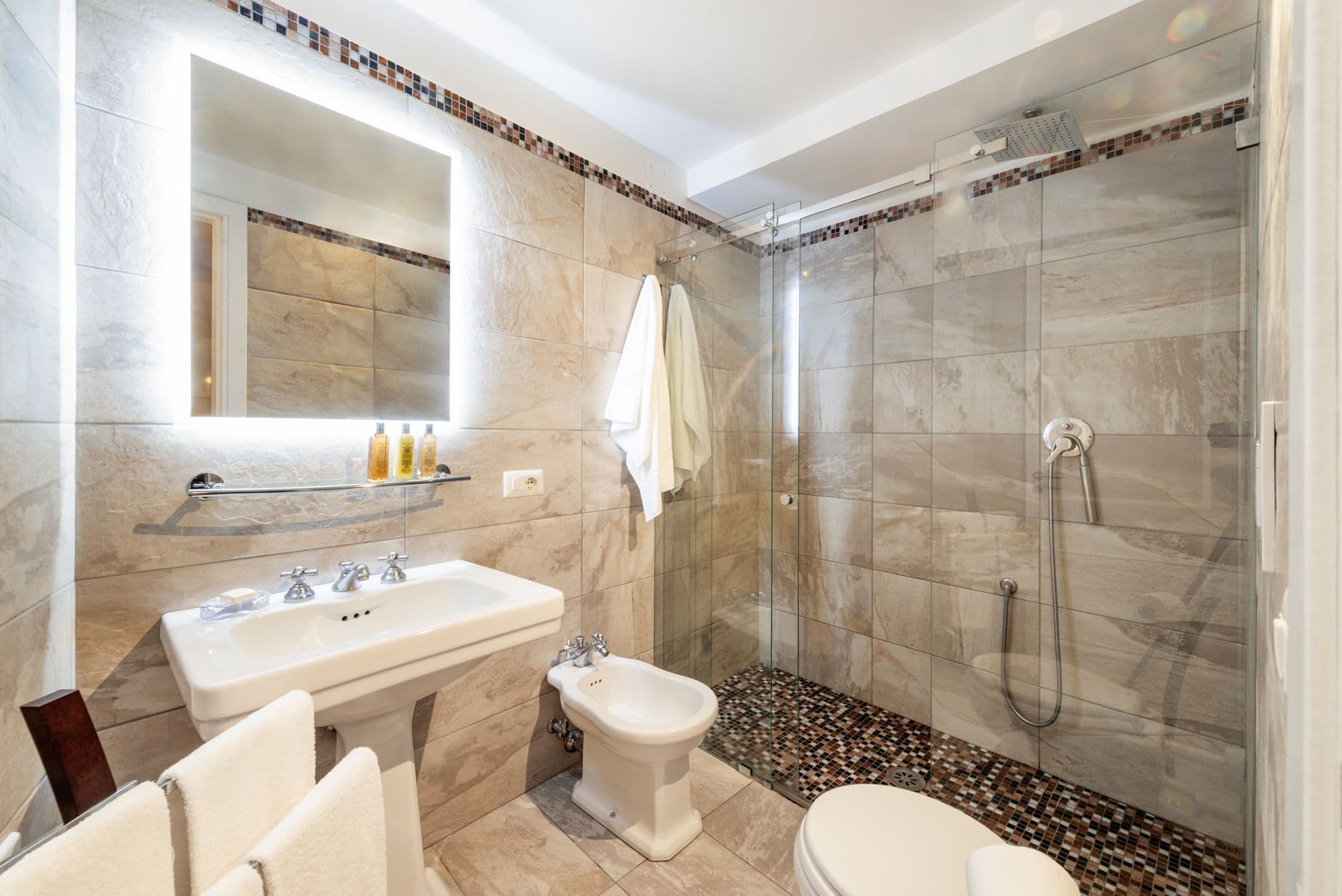 Marble bathroom with a walk-in shower and backlit mirror at Arch Above the Sea, Amalfi Coast