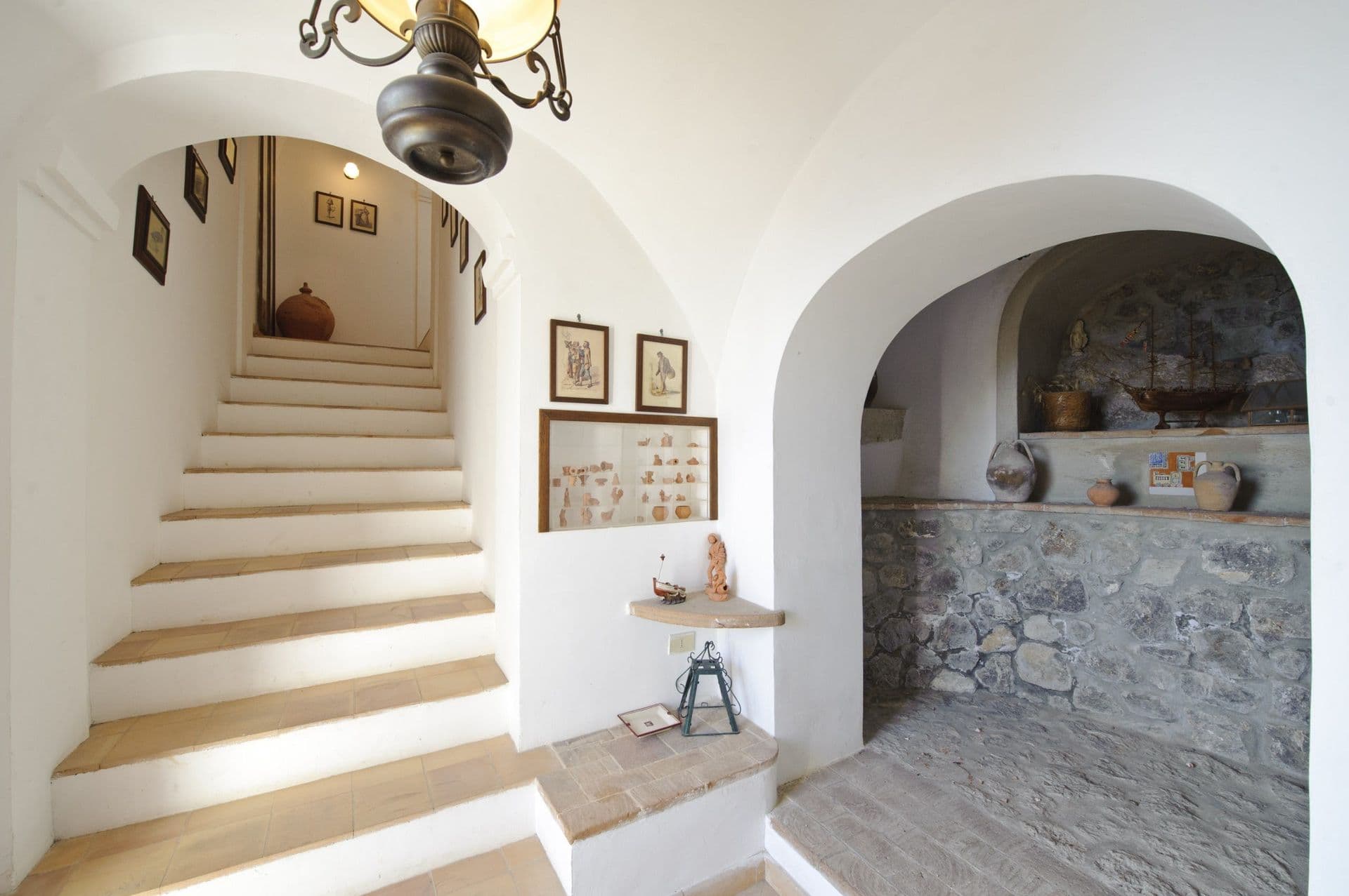 Whitewashed vaulted staircase with a stone niche at Arch Above the Sea, Amalfi Coast