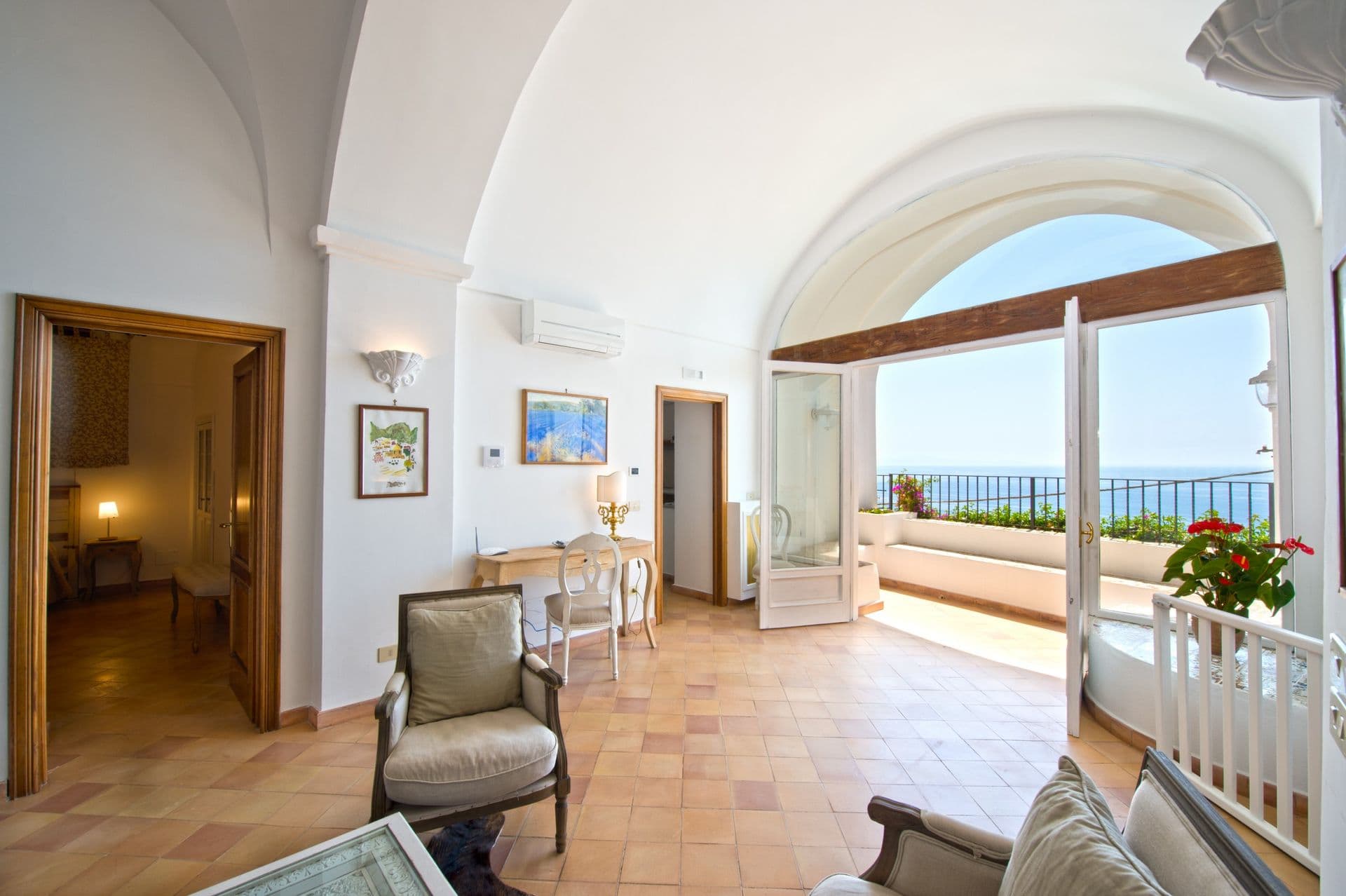 Vaulted sitting room opening through an arched window to a sea-view terrace at Arch Above the Sea, Amalfi Coast