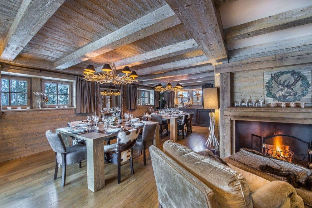 Dining room with a long table, chandelier and fireplace at Meribel 139