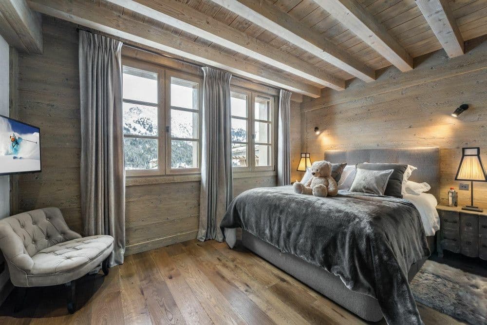 Guest bedroom with a grey fur throw and reading chair at Meribel 139