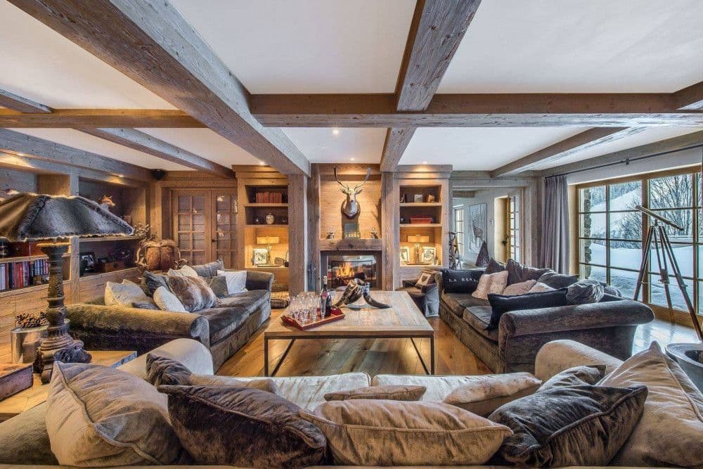 Beamed living room with velvet sofas and a stone fireplace at Meribel 139