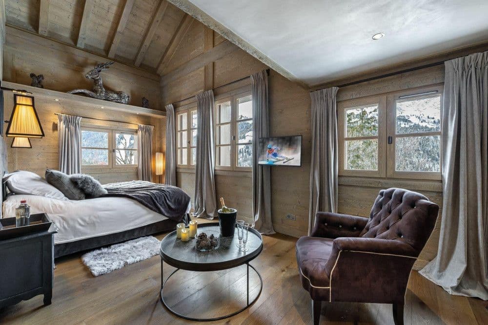 Master bedroom with mountain windows and a reading chair at Meribel 139