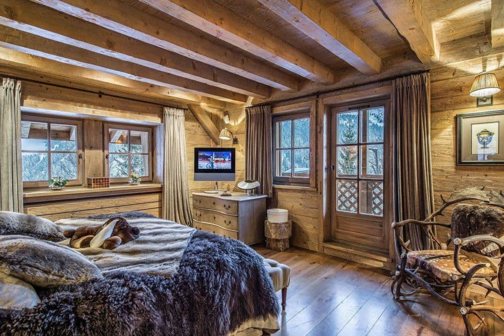 Double bedroom with fur throws and a mountain window at Meribel 139