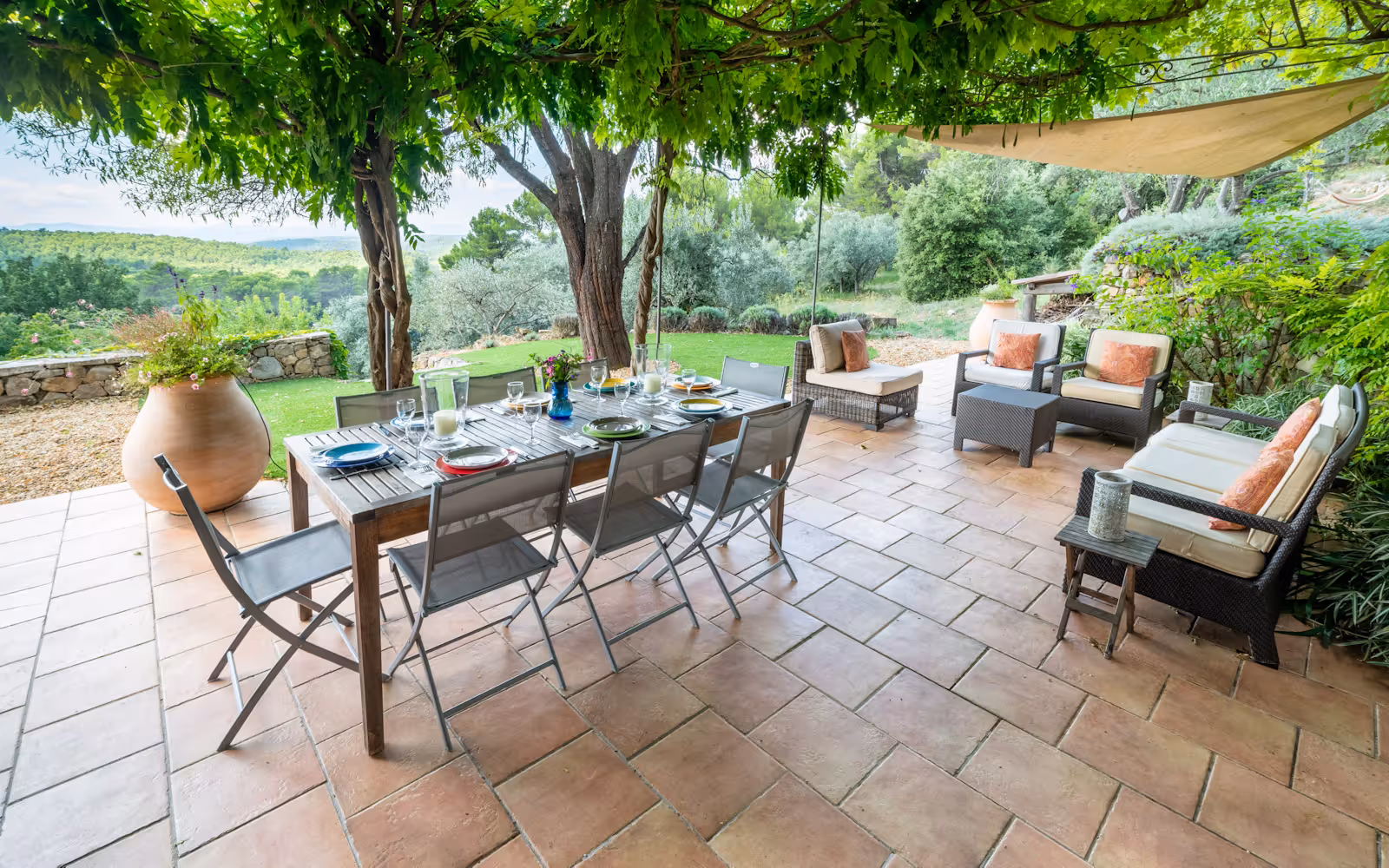 Terracotta terrace with an outdoor dining table and sofas overlooking the valley at Choral Words, Var, Provence