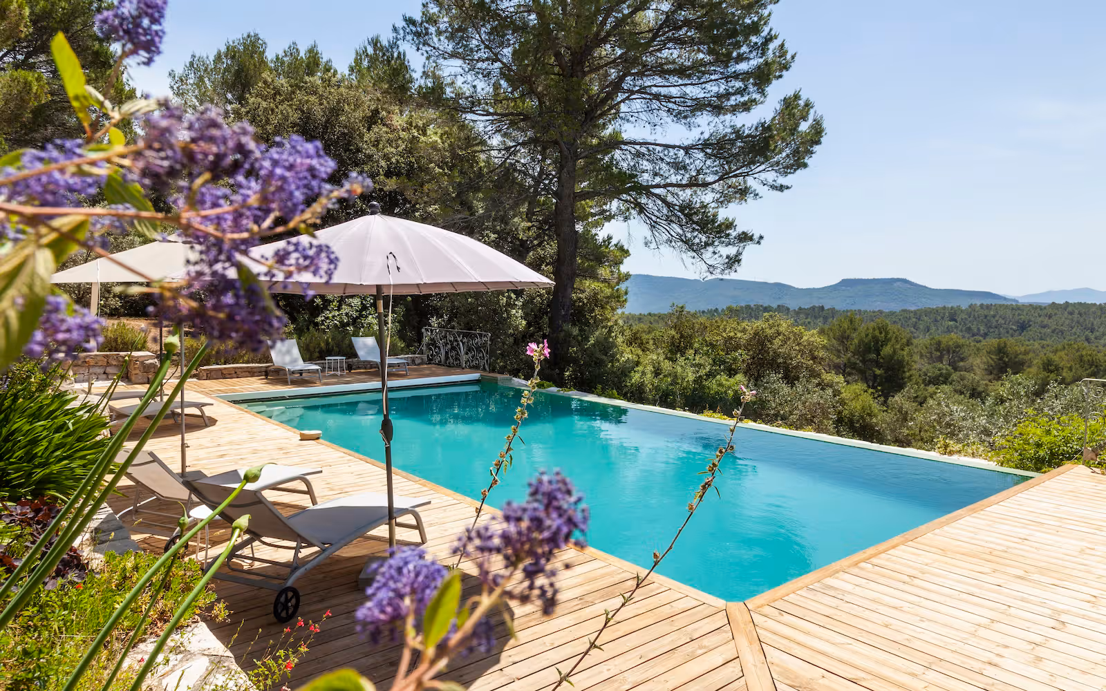 Swimming pool on a timber deck framed by lavender and hills at Choral Words, Var, Provence
