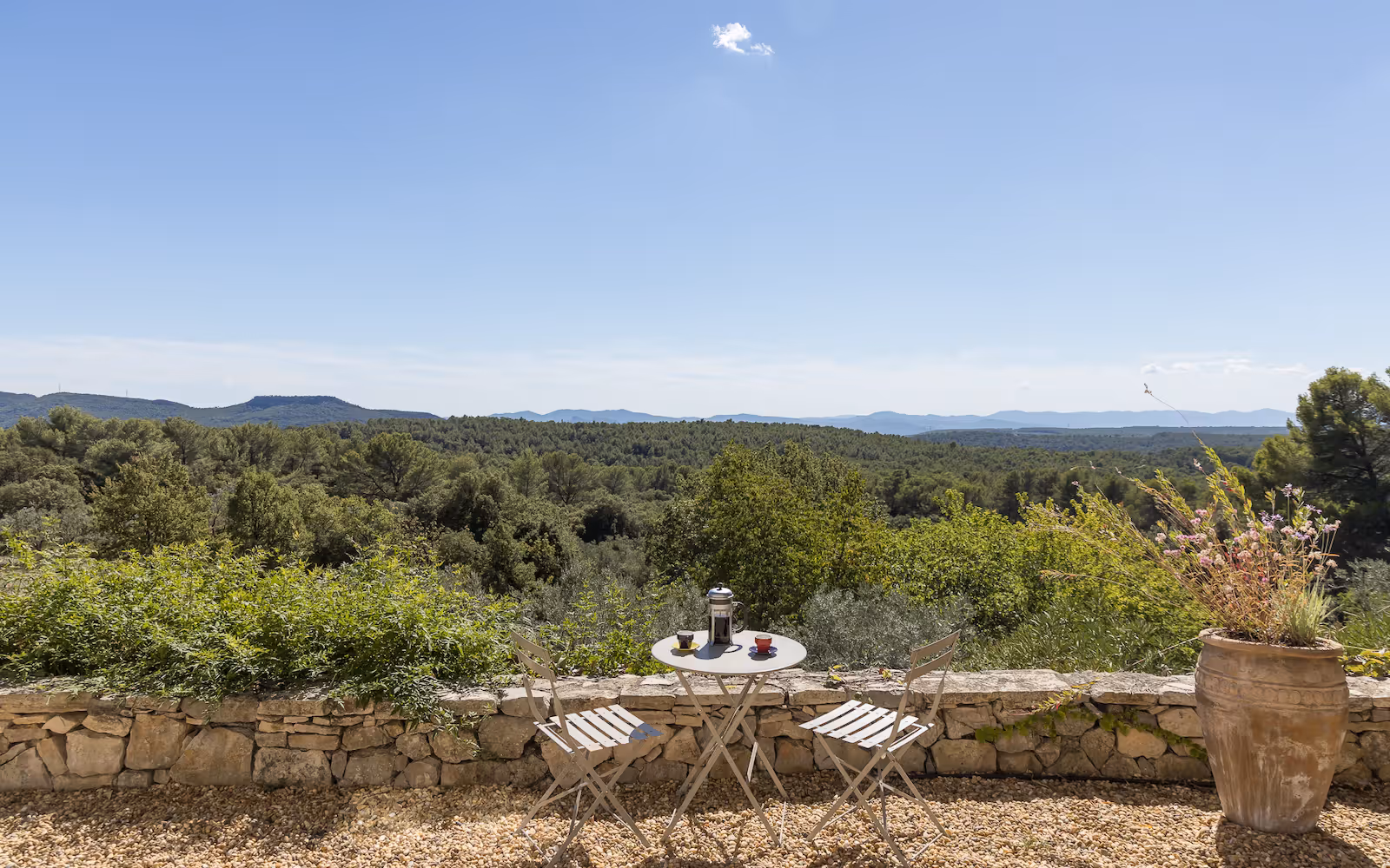 Bistro table on a stone-walled terrace above a panorama of wooded hills at Choral Words, Var, Provence