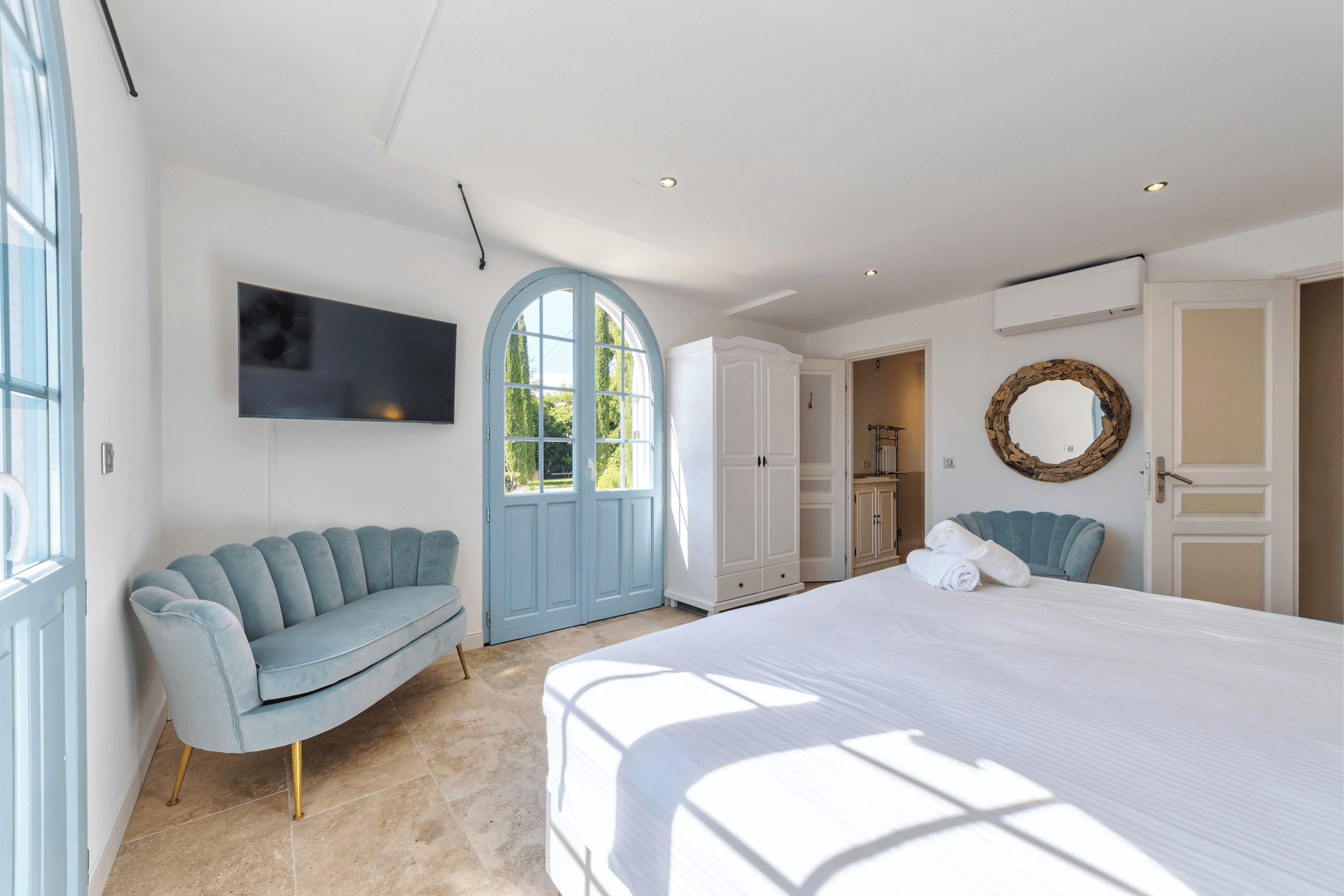 A bedroom with a duck egg velvet sofa and arched garden doors