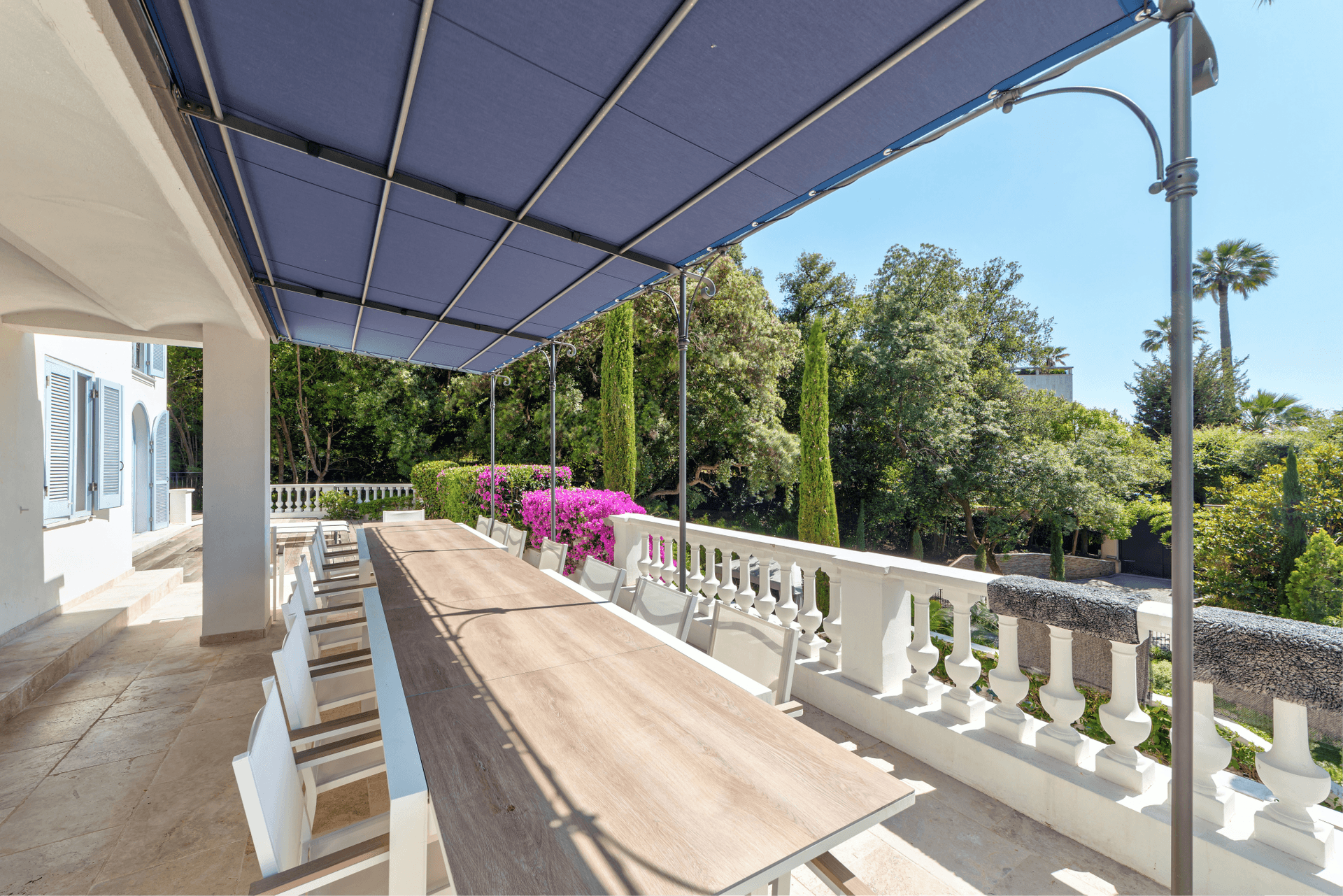 A long shaded dining terrace with balustrade overlooking the gardens at The Lark's Song