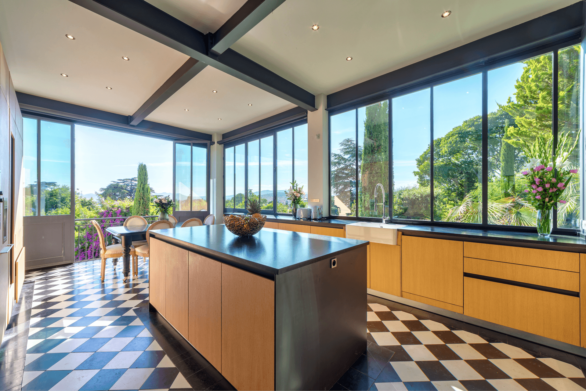 A timber kitchen island beneath a glazed pitched roof with garden views