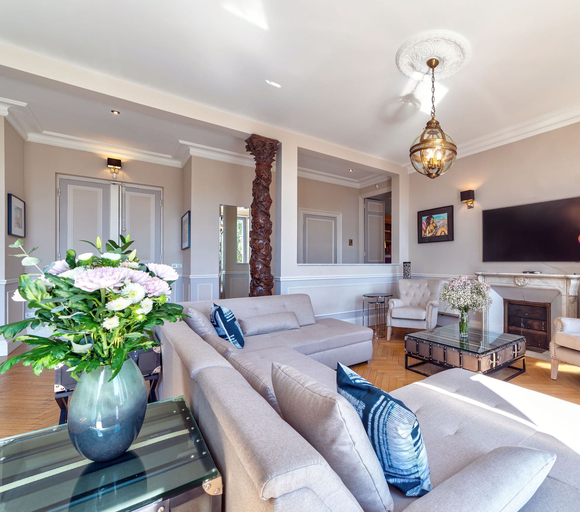A classic salon with cream sofas, herringbone parquet flooring and fresh flowers