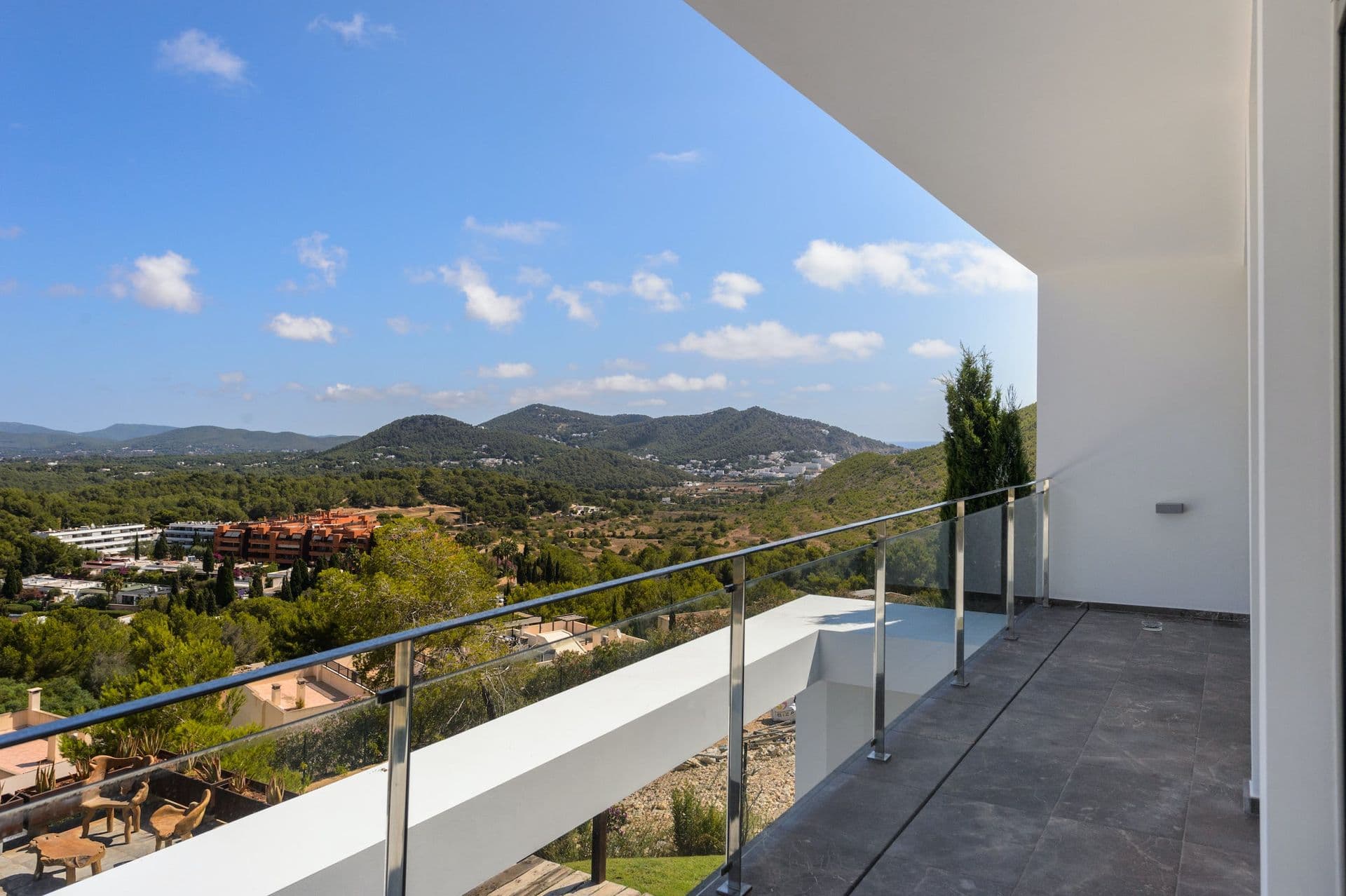 Private balcony with glass balustrade overlooking the wooded Ibizan hills