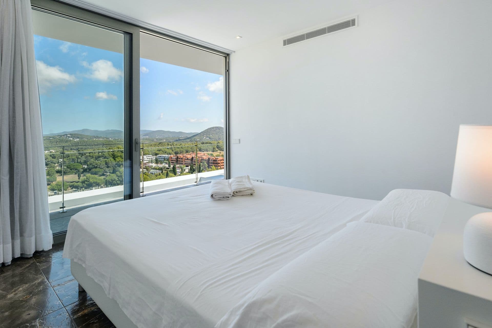 Bright double bedroom with floor-to-ceiling windows onto the hills