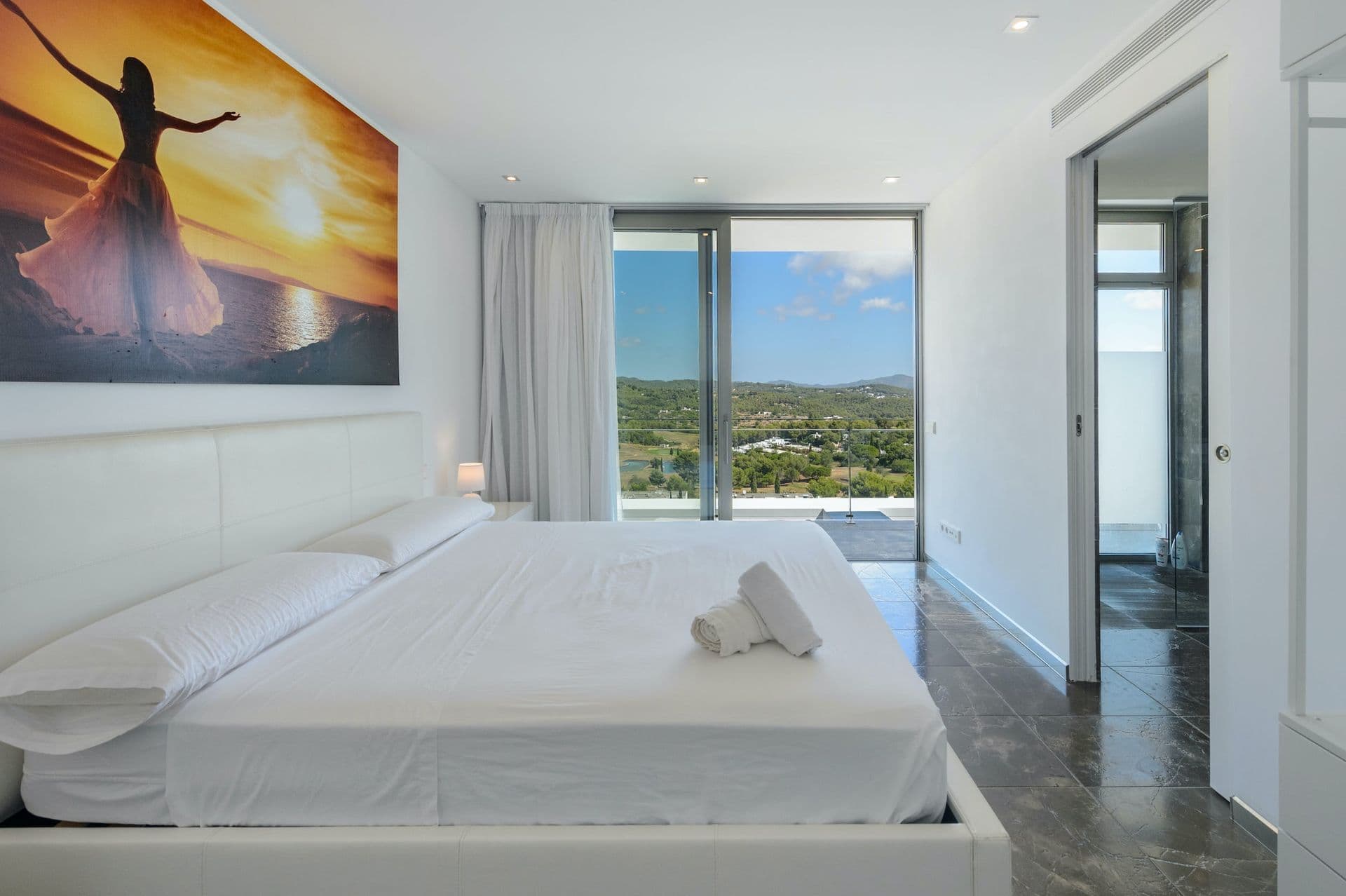 Bedroom with a statement sunrise artwork and glass doors onto a balcony