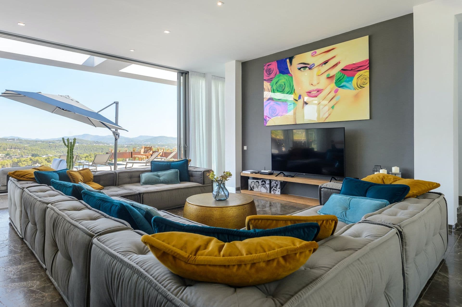 Living room with grey corner sofas, mustard and teal cushions and pop art