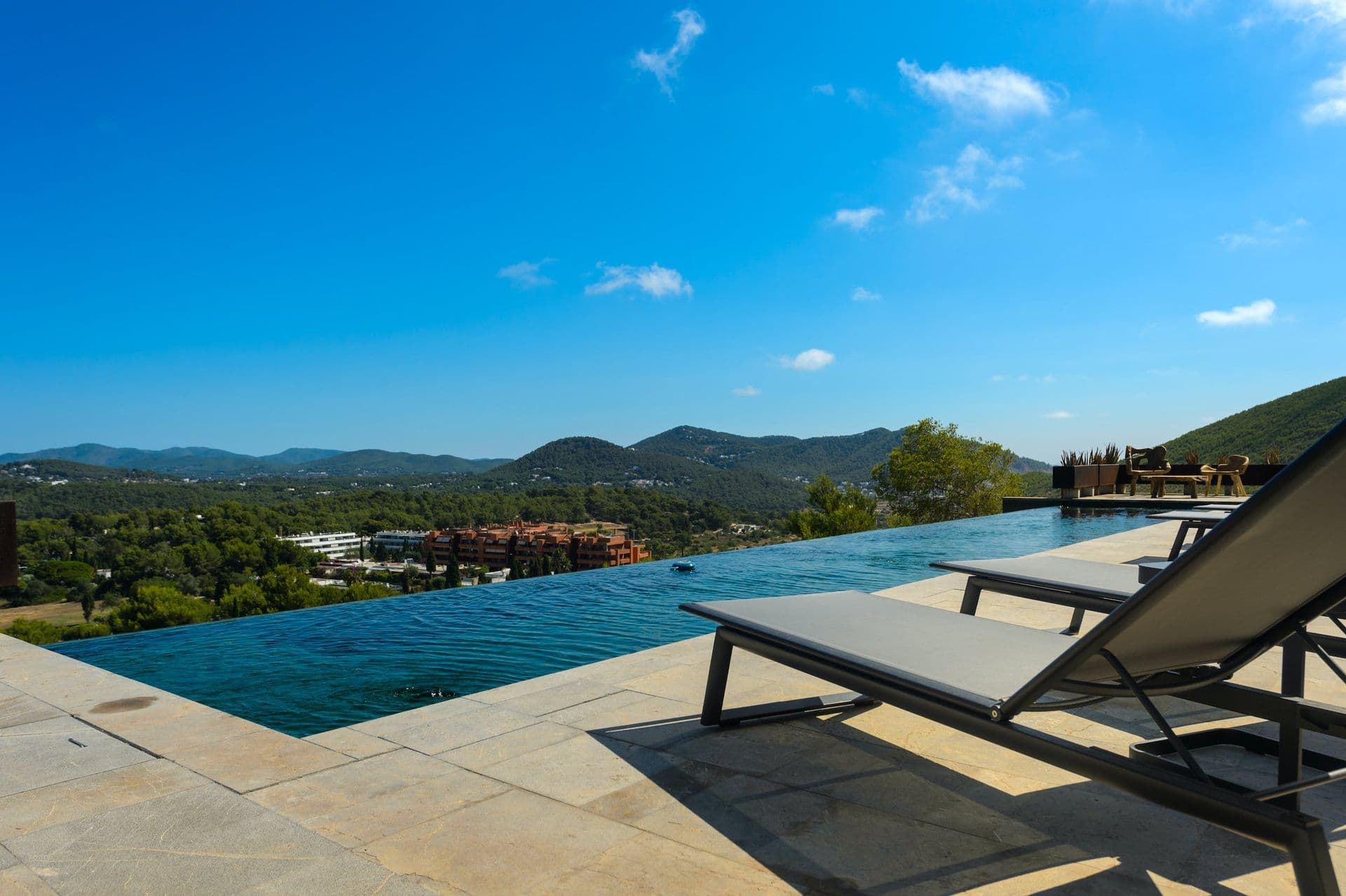 Infinity pool with sun loungers set against sweeping Ibizan hillside views