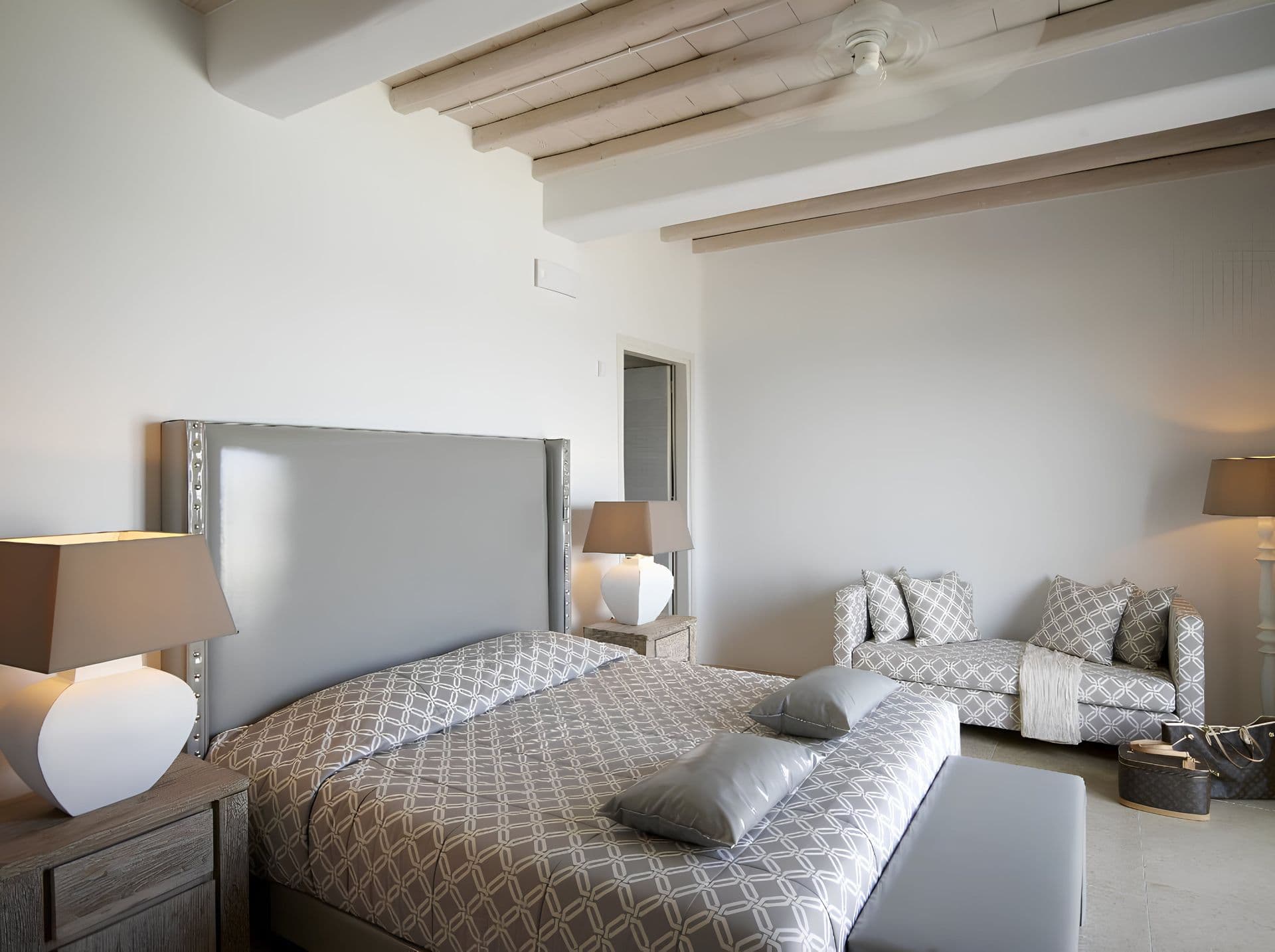 Bedroom with a grey quilted bedspread and bedside lamps.