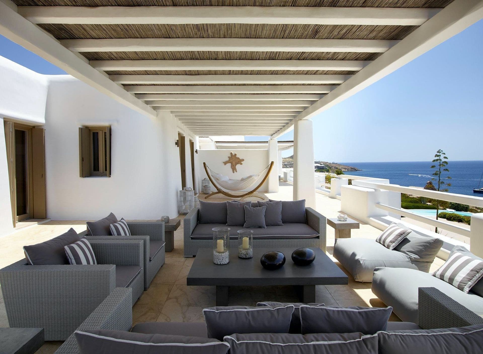 Covered lounge terrace with grey outdoor sofas and sea views.