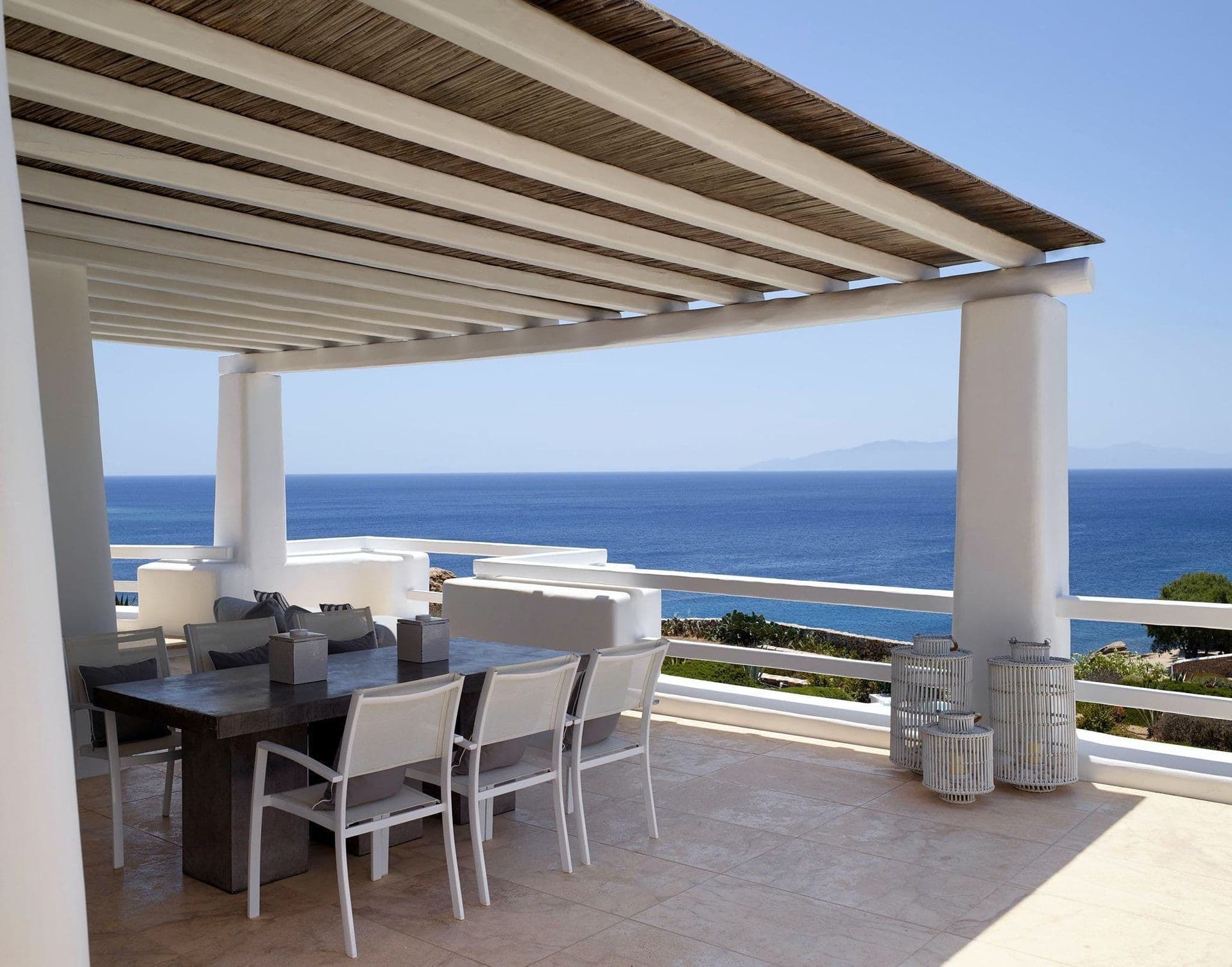Wood beamed pergola terrace with a dining table set for a sea view lunch.