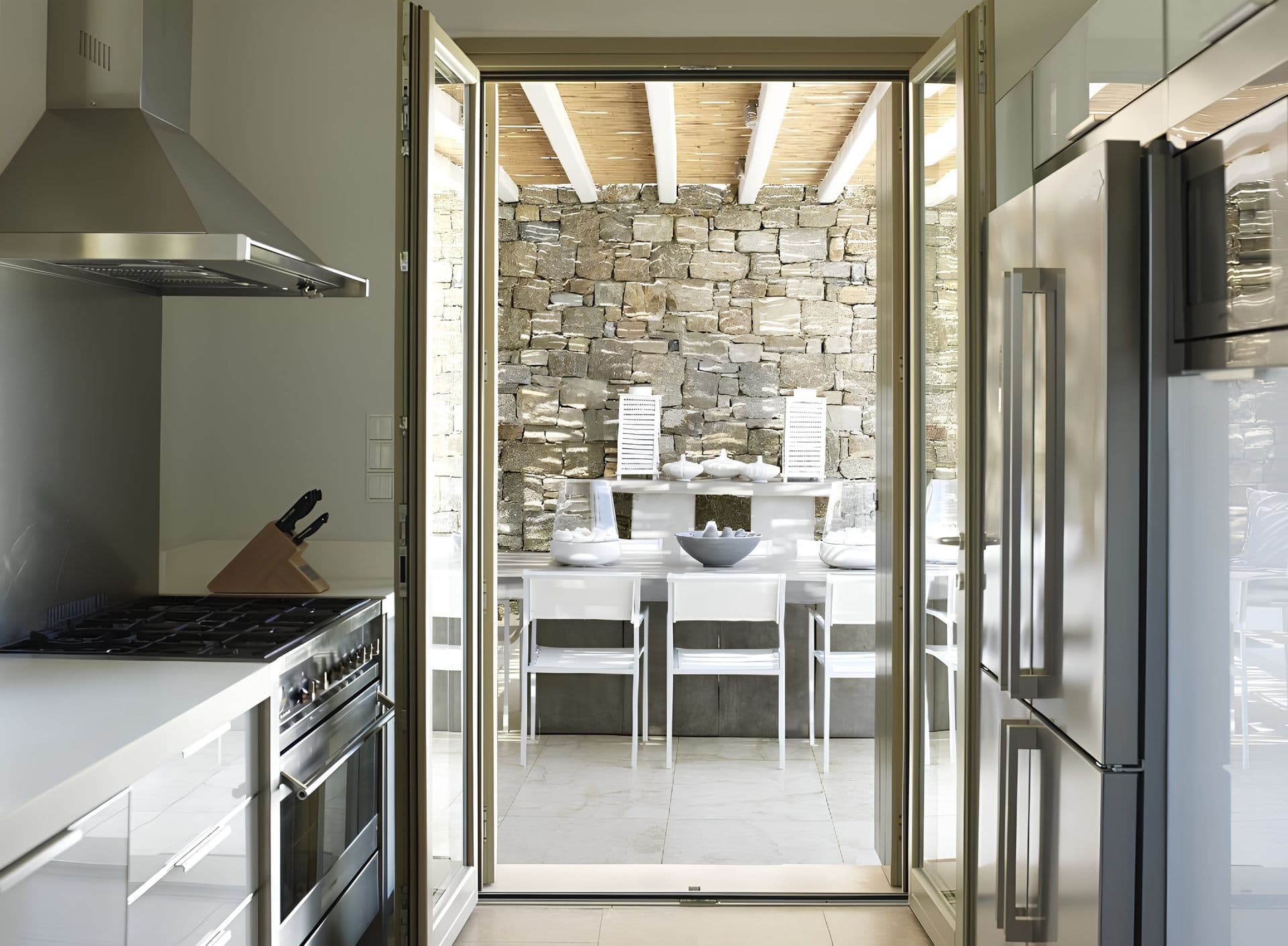 Kitchen with stainless steel appliances opening onto a stone walled dining area.