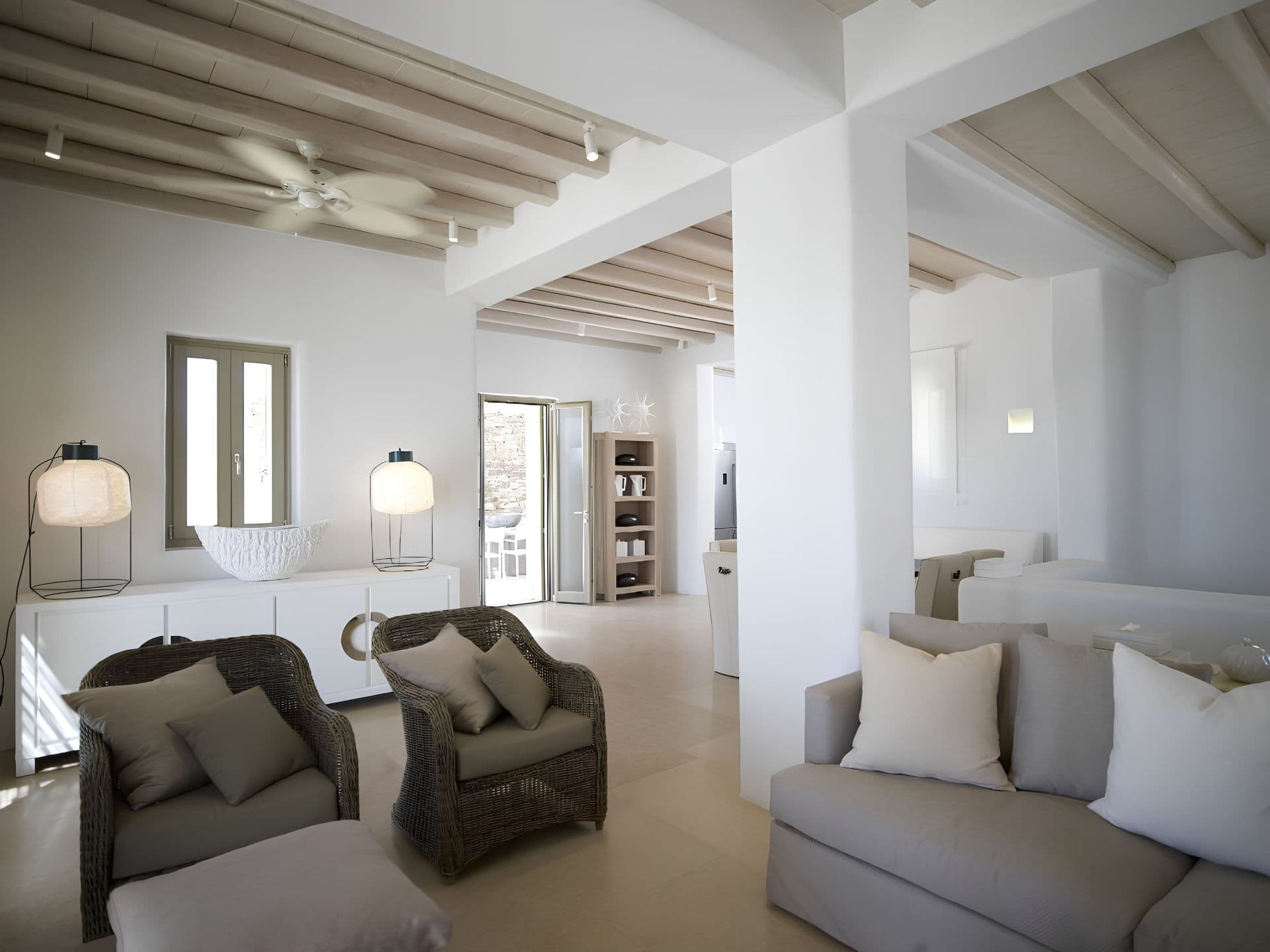 Open plan living and dining area lit by woven pendant lanterns.