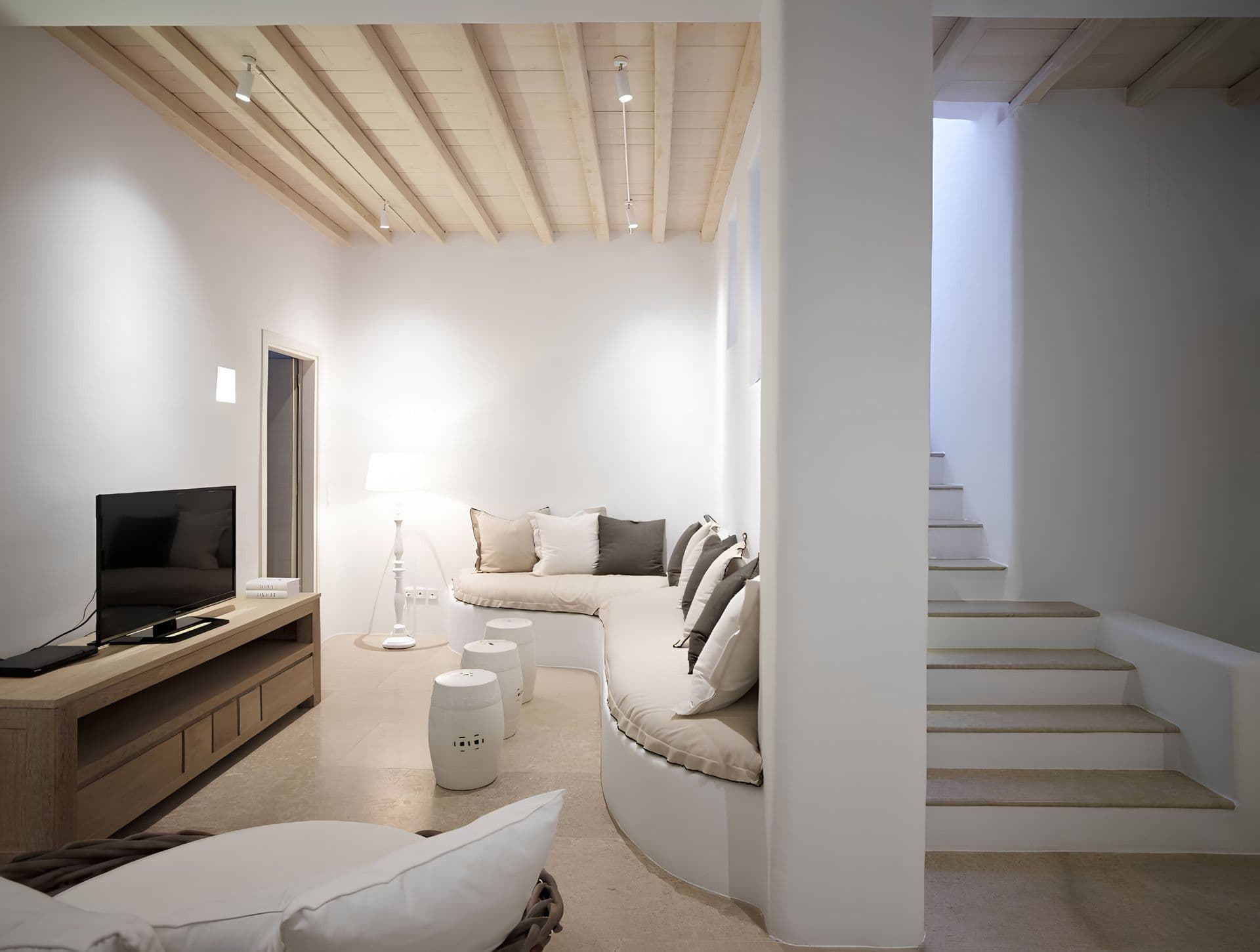 Living room with a curved white staircase and a built in TV unit.