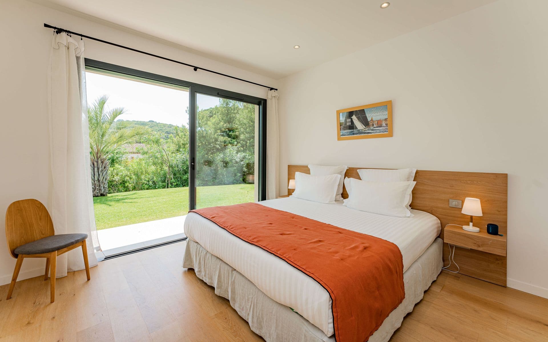 Bedroom with a terracotta-red throw and direct garden access.