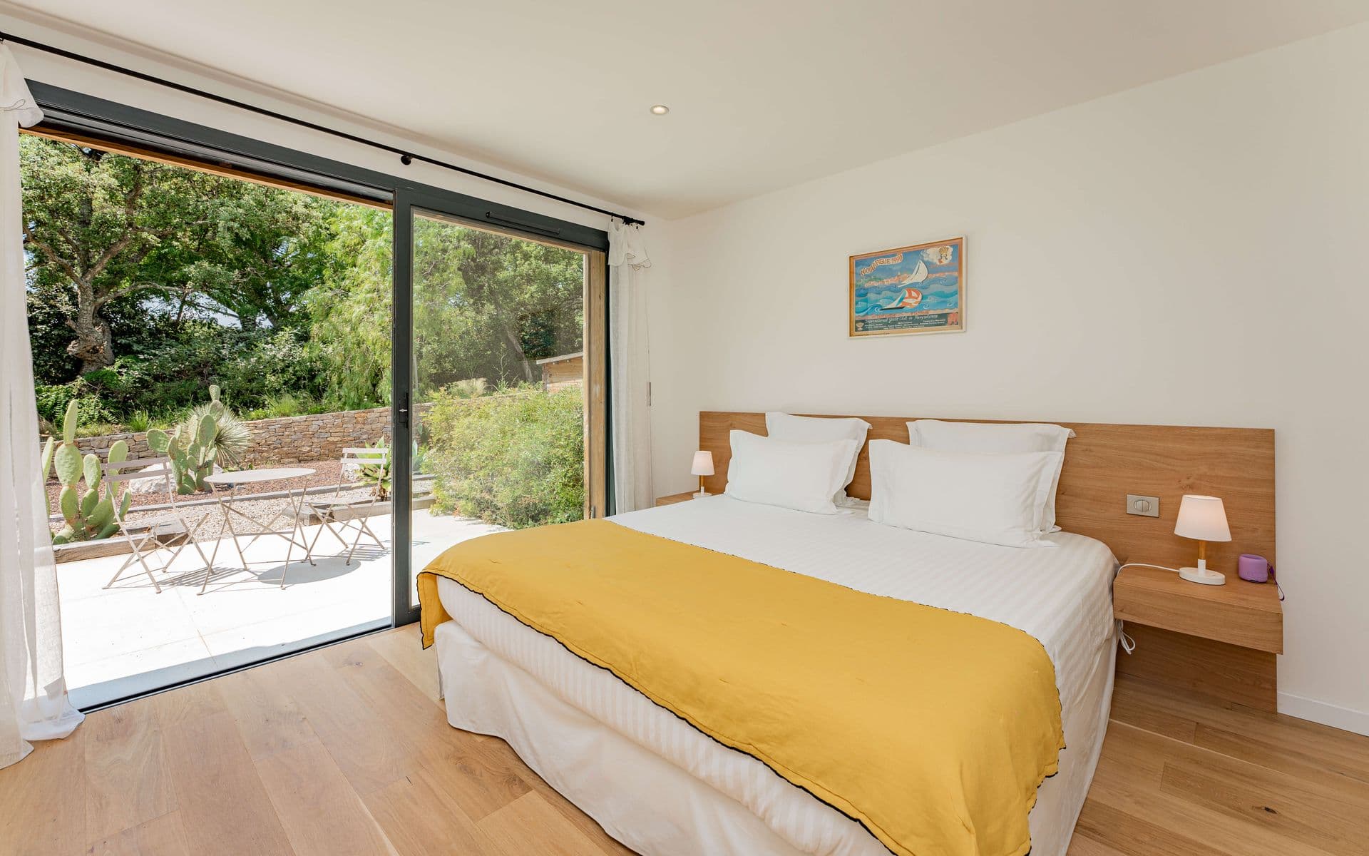 Bedroom with a mustard-yellow throw and sliding doors onto the terrace.