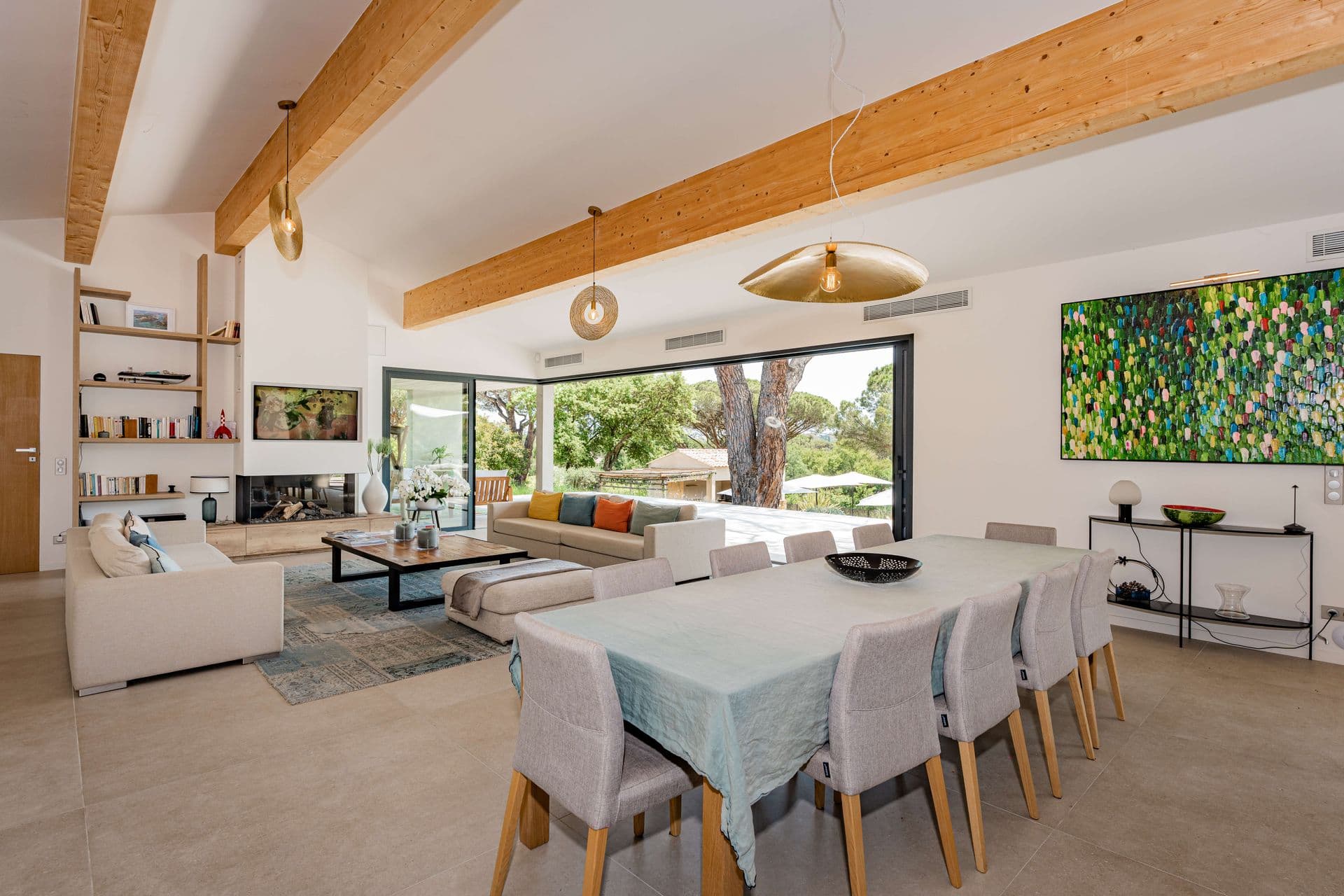 Dining room seating ten beneath exposed wood beams and contemporary art.