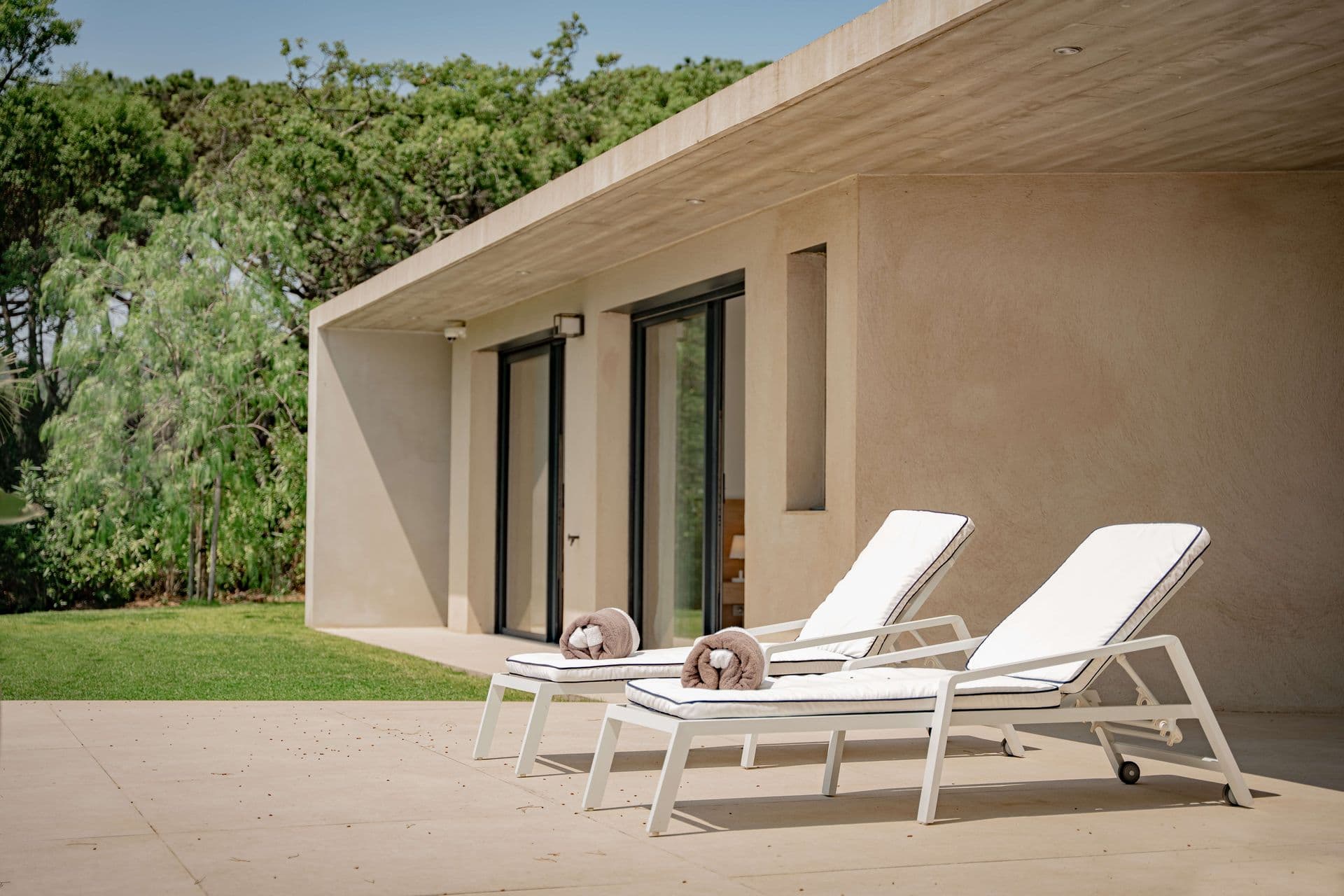 Modern villa wing with sun loungers on a private terrace.