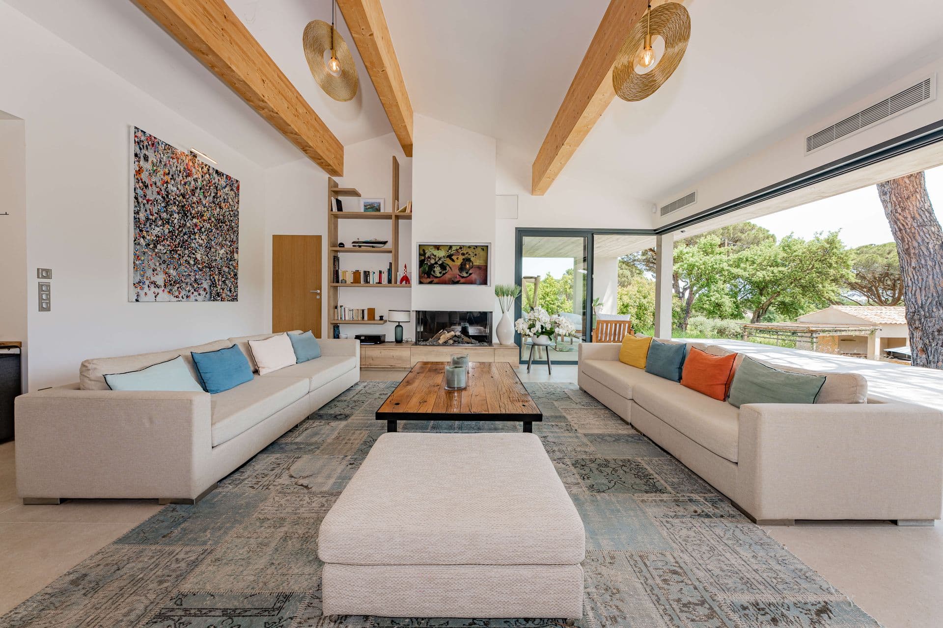 Living room with beamed ceiling, white sofas and colourful accent cushions.