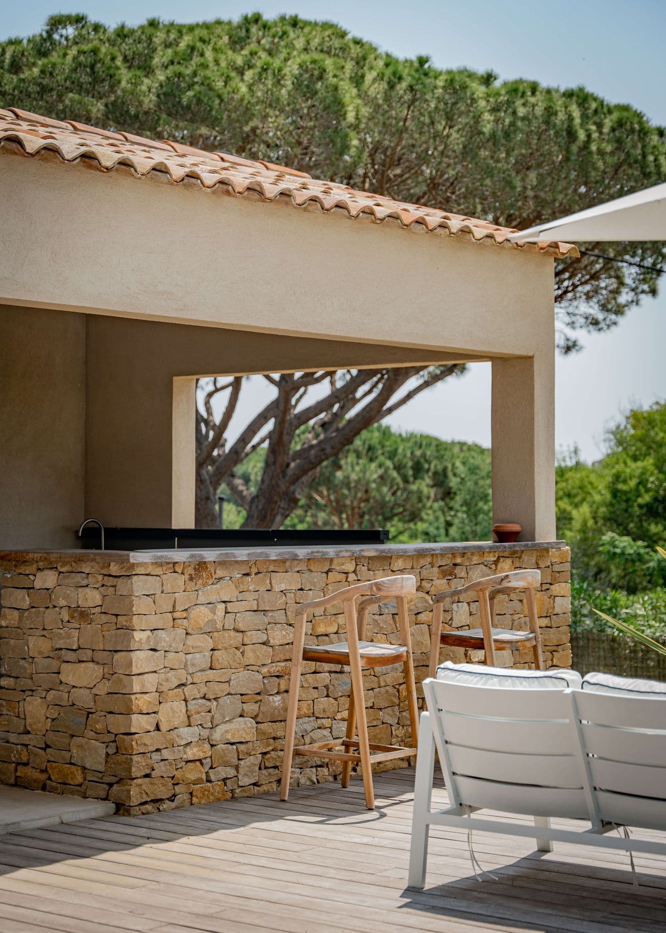Stone-built outdoor bar with counter seating beneath the pines.