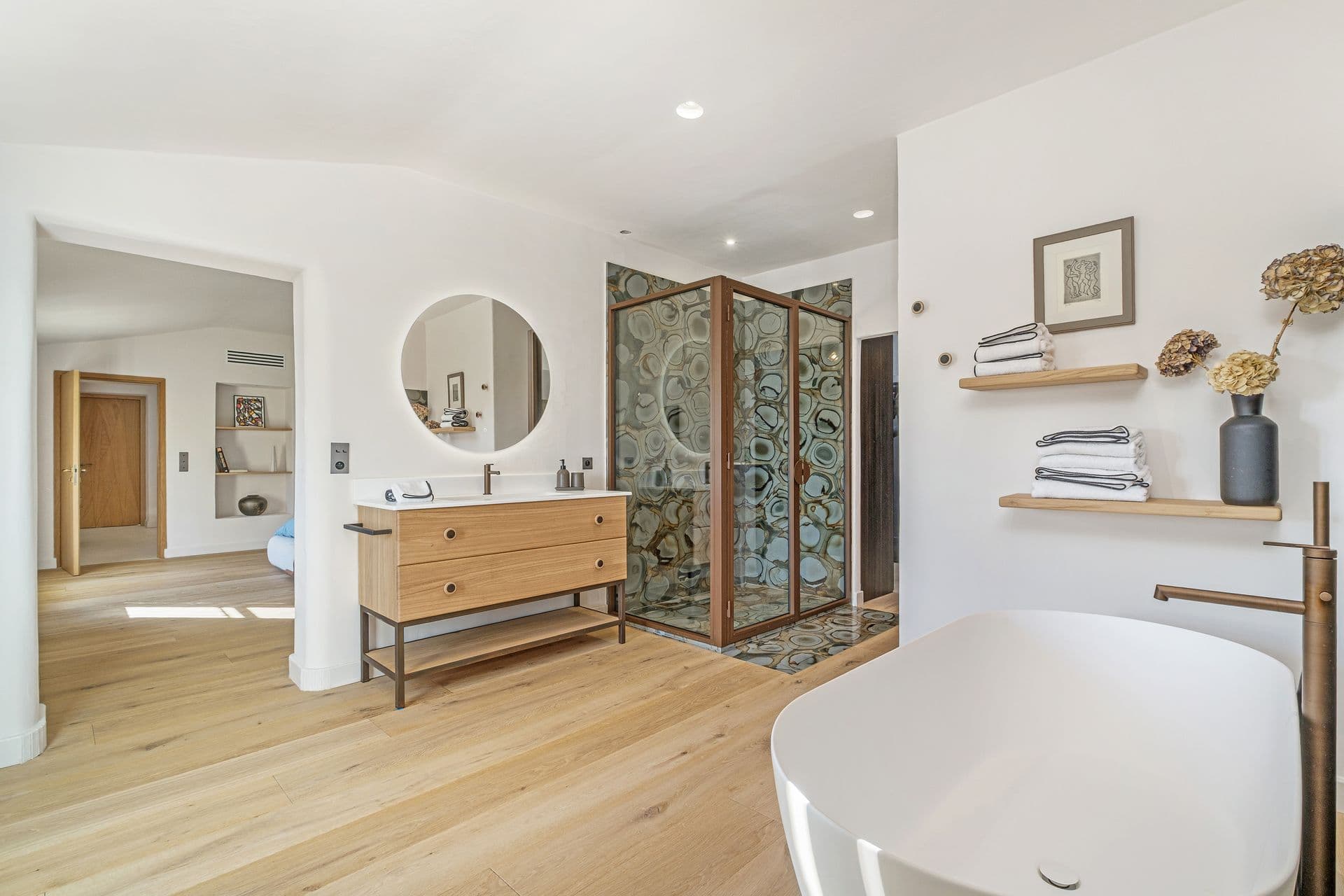 Bathroom with a round mirror, wood vanity and freestanding tub