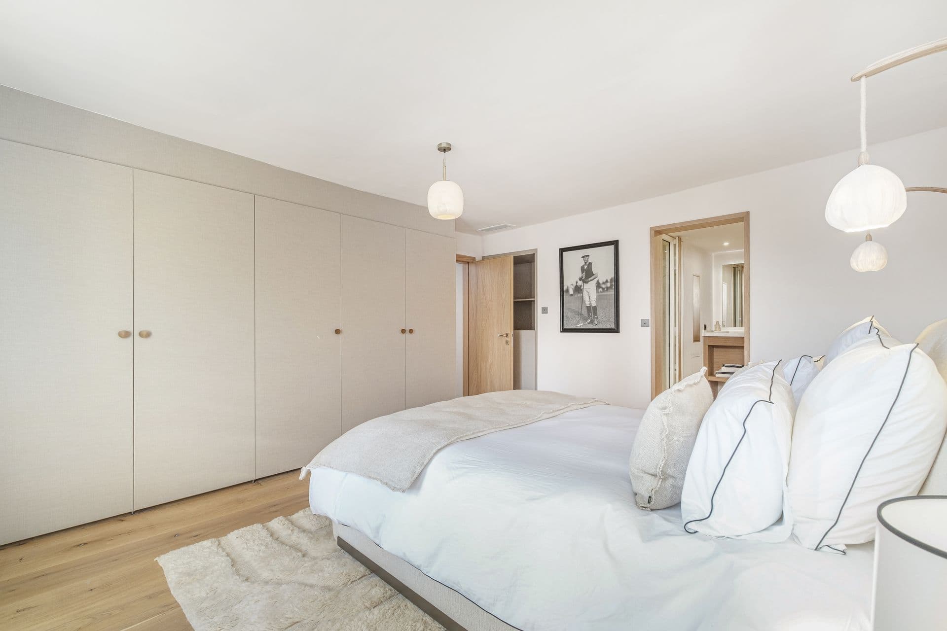 Bedroom with white bedding and full-height fitted wardrobes