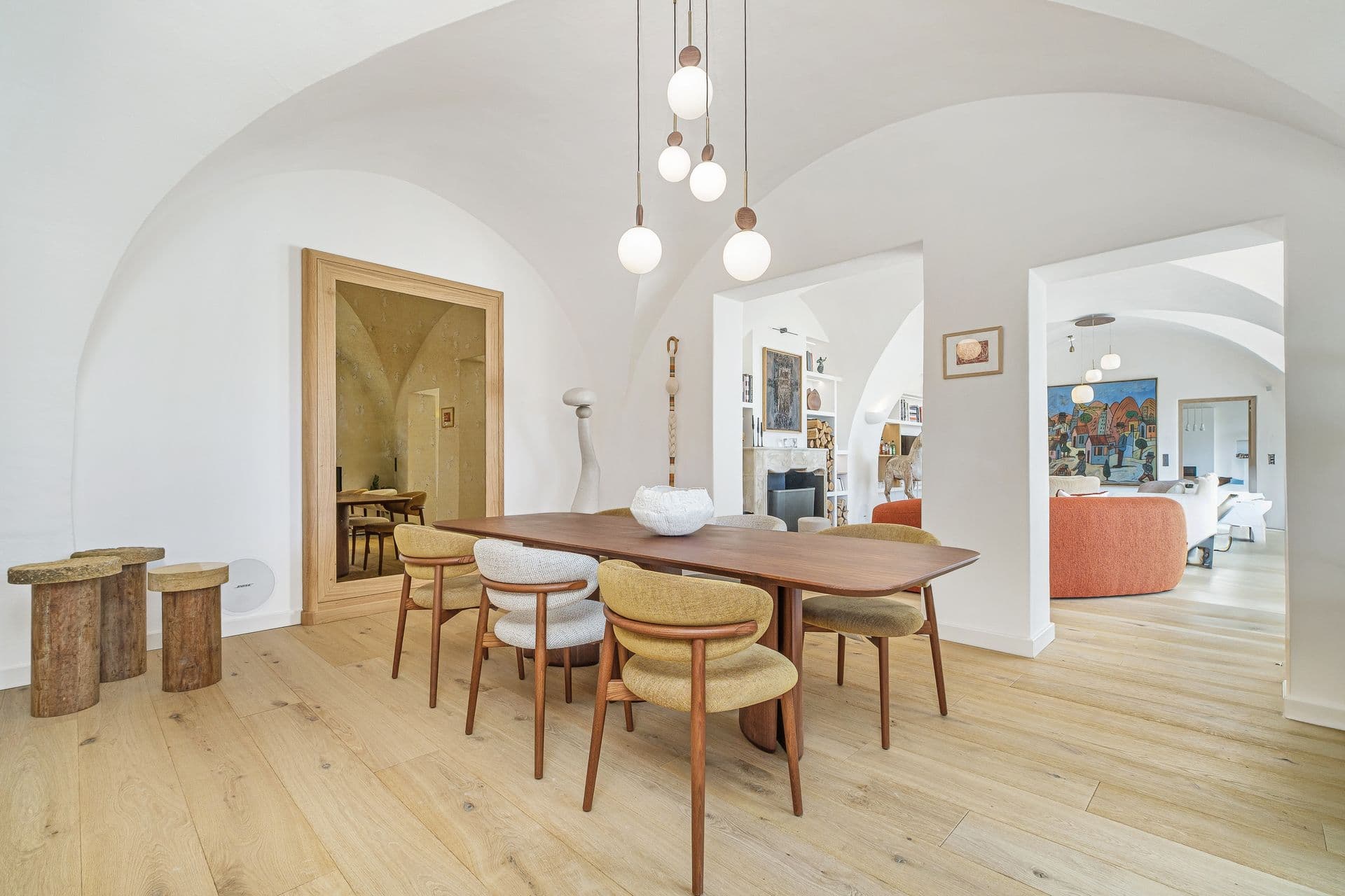 Dining room with a wooden table beneath vaulted arched ceilings and pendant lighting