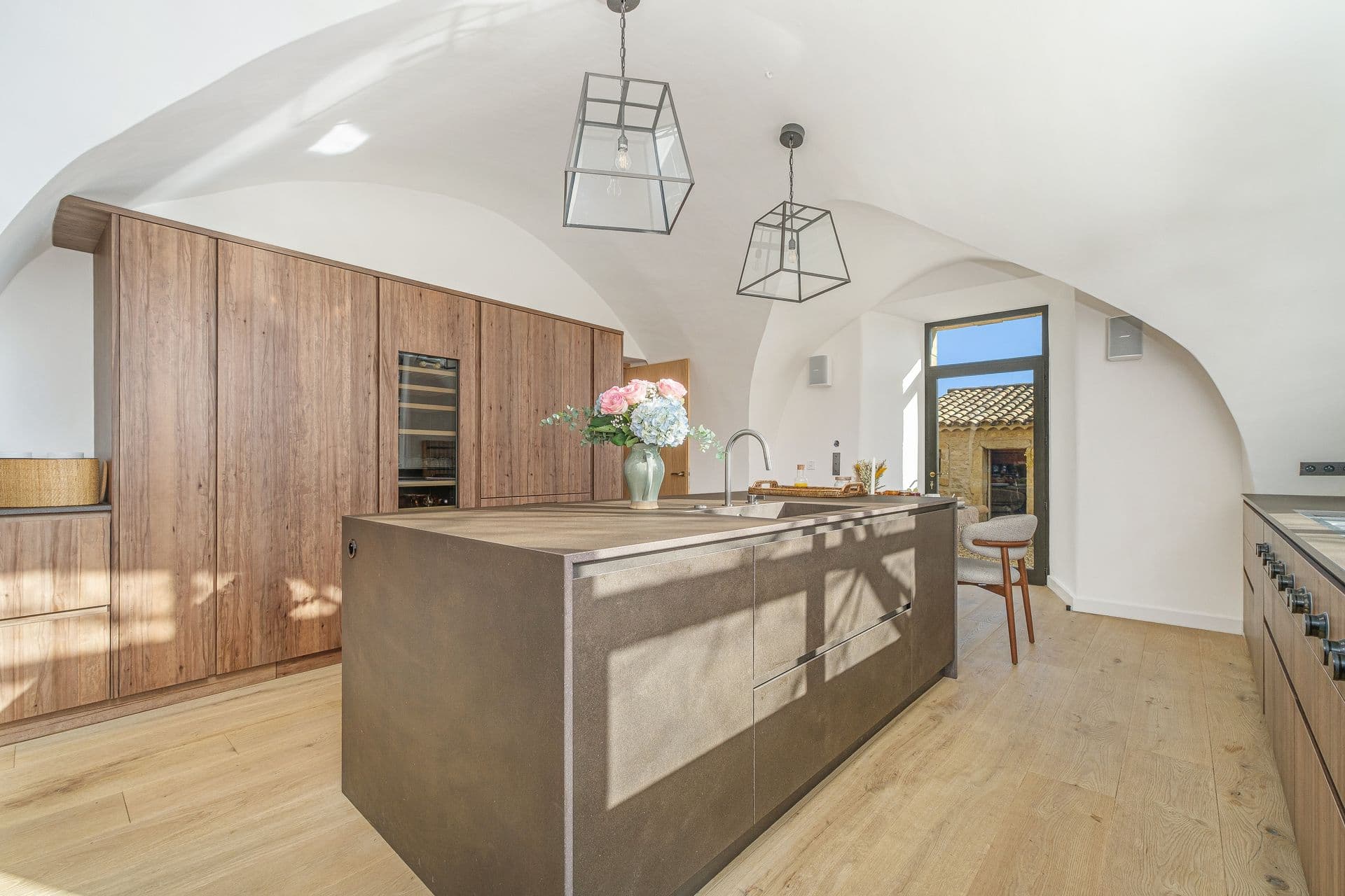Dark wood kitchen island with built-in shelving and warm pendant lighting