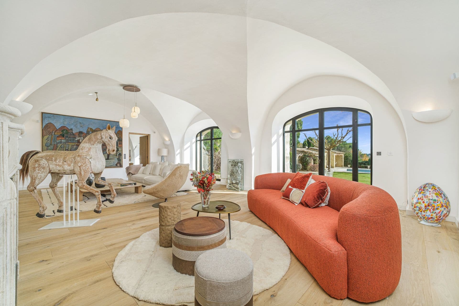 Living room with vaulted arched ceiling, orange curved sofa and sculptural horse artwork