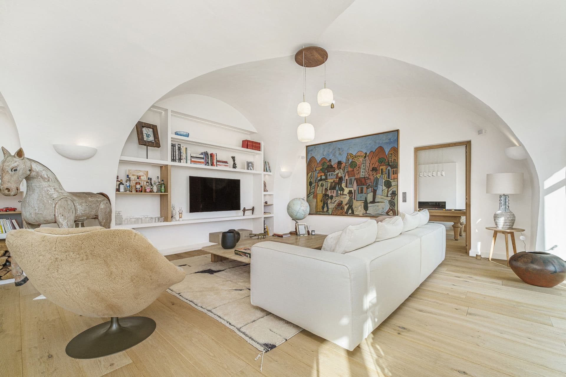 Living room with white sofas and arched alcoves beneath a vaulted ceiling