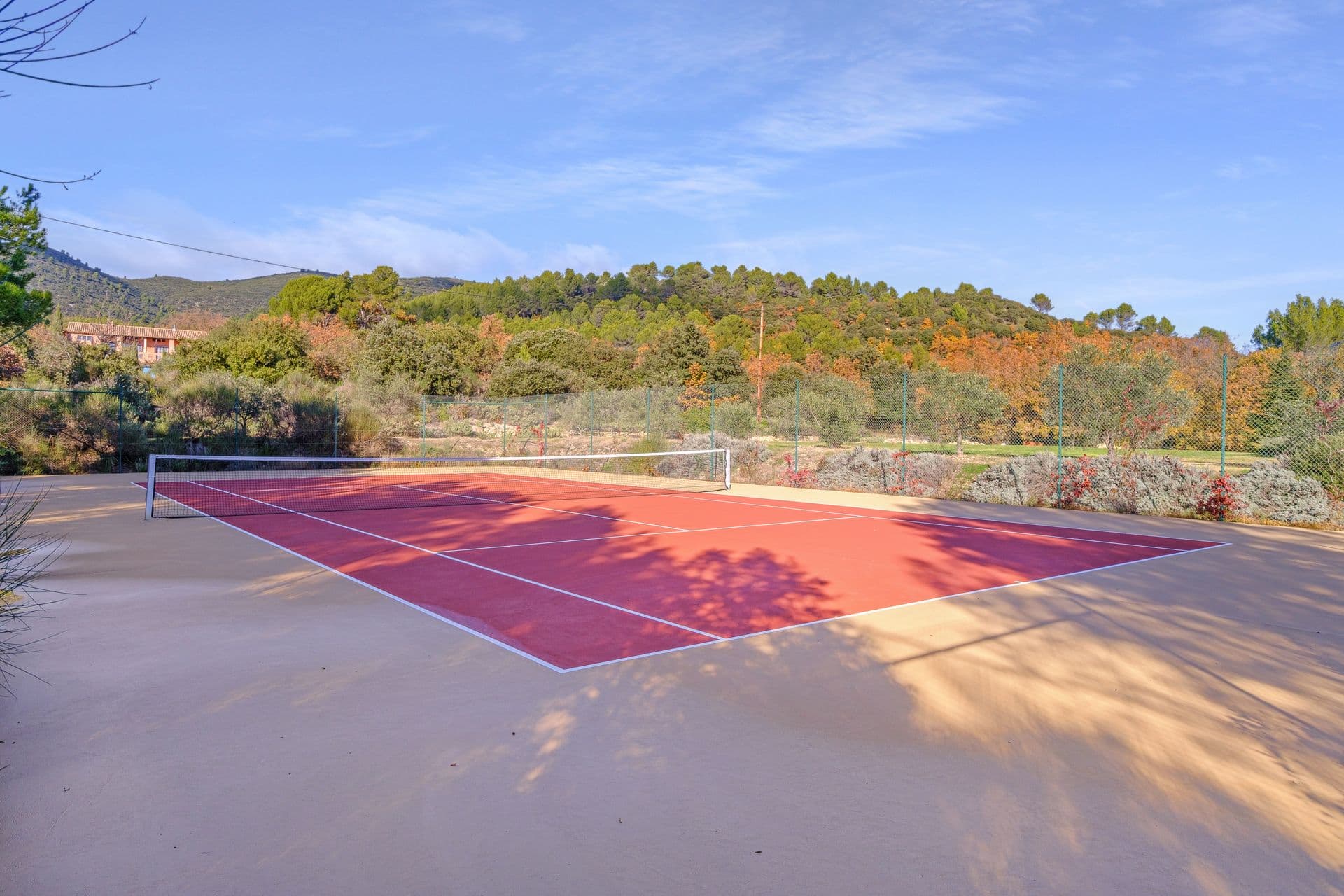Private tennis court surrounded by trees and countryside