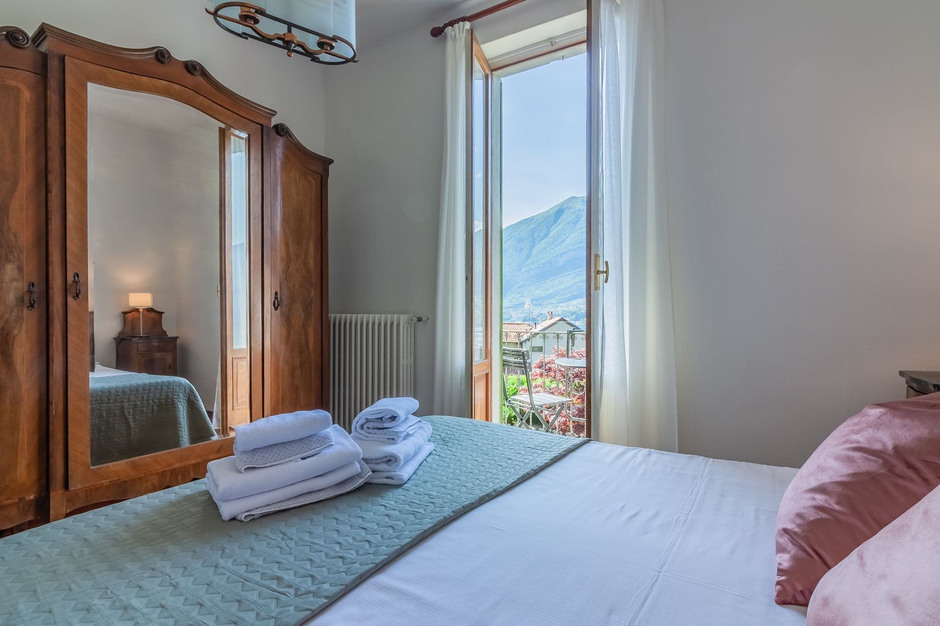 Bedroom with green bedspread and balcony doors overlooking the lake at So Bellagio