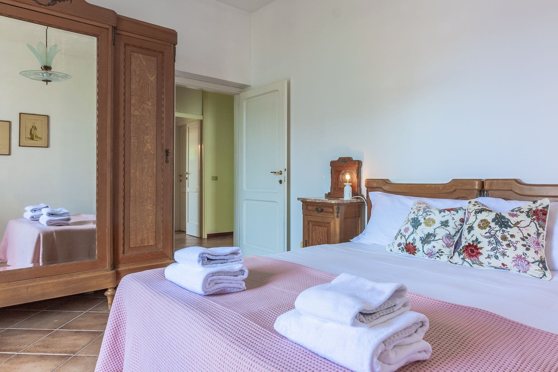 Bedroom with floral bedspread and wooden wardrobe at So Bellagio